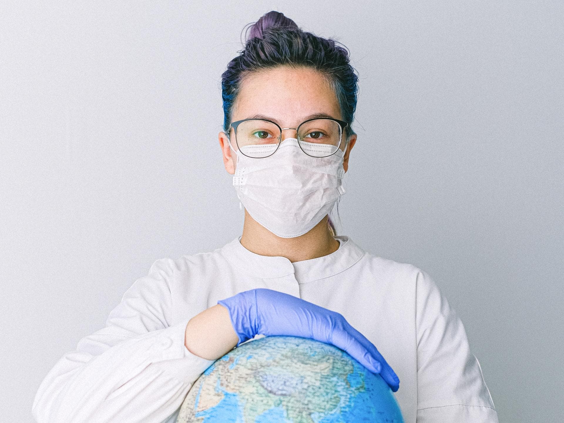 Frau mit Maske hat Globus in der Hand