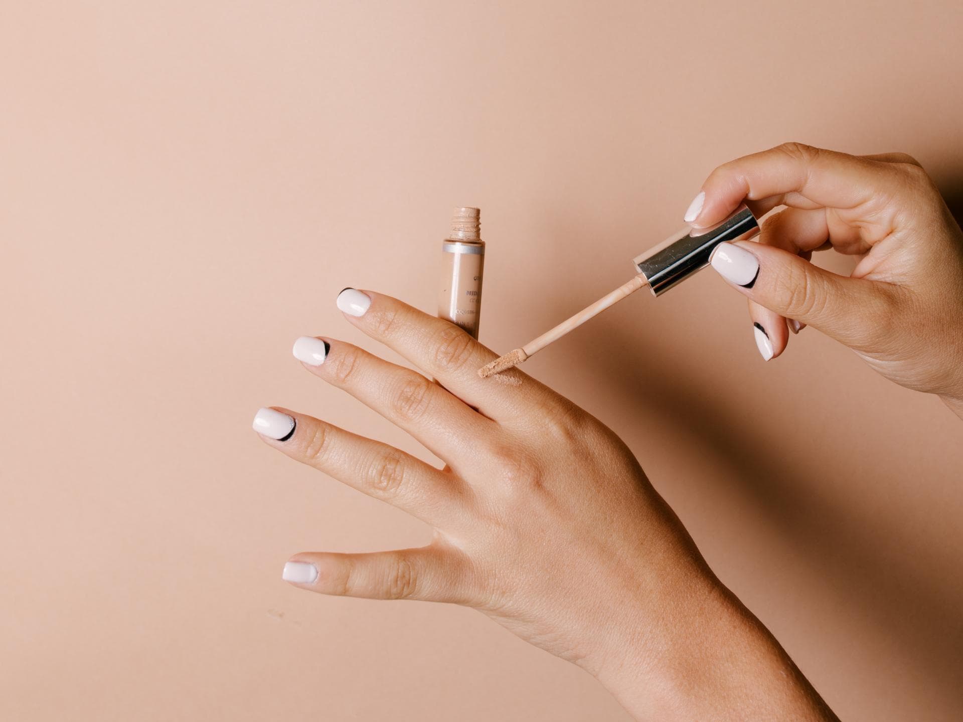 Concealer wird auf Hand aufgetragen