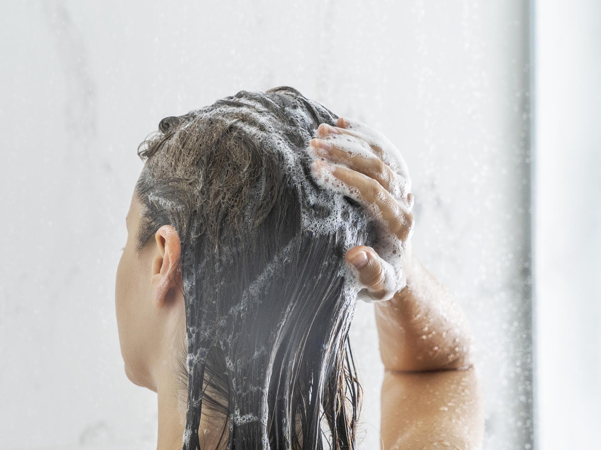 Mildes Shampoo für empfindliche Kopfhaut Frau wäscht sich die Haare mit Shampoo