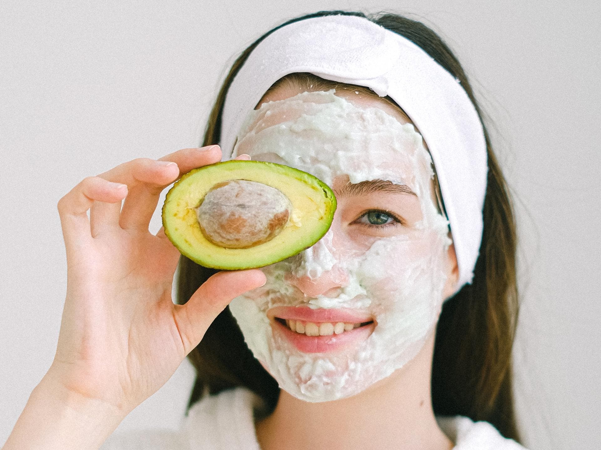 Frau mit Gesichtsmaske und Avocado