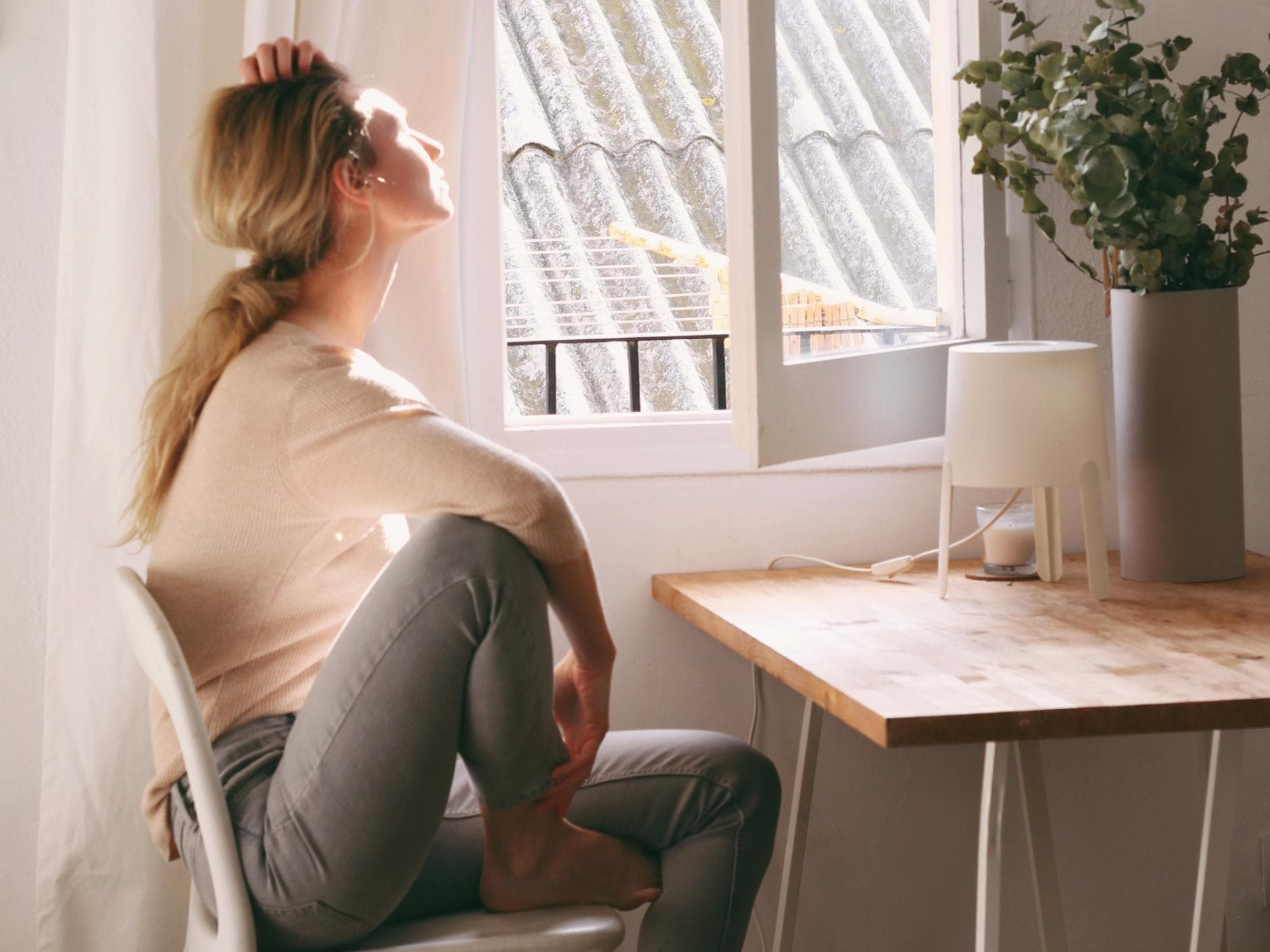 Frau schaut müde aus dem Fenster