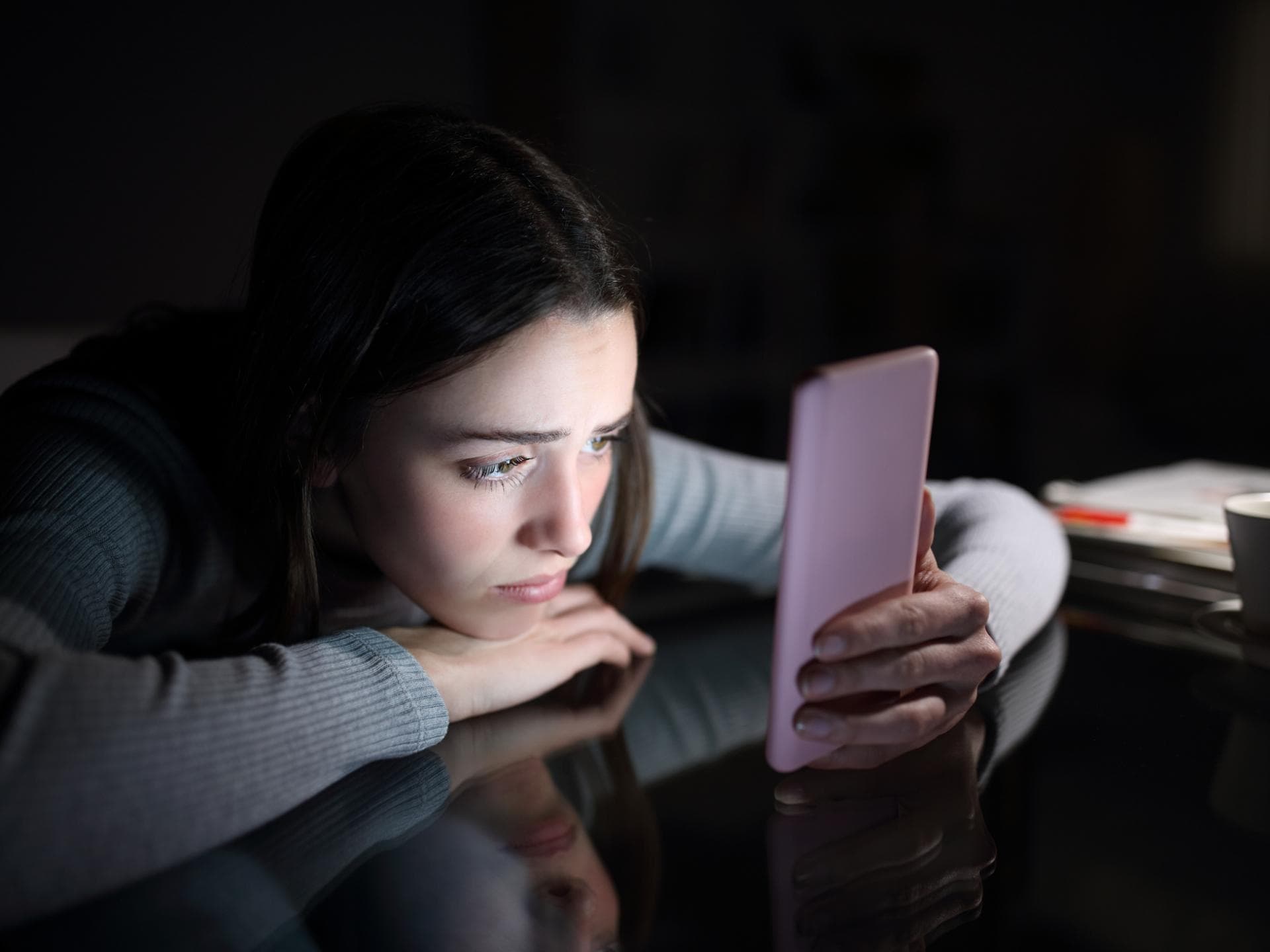 Frau guckt traurig auf ihr Smartphone