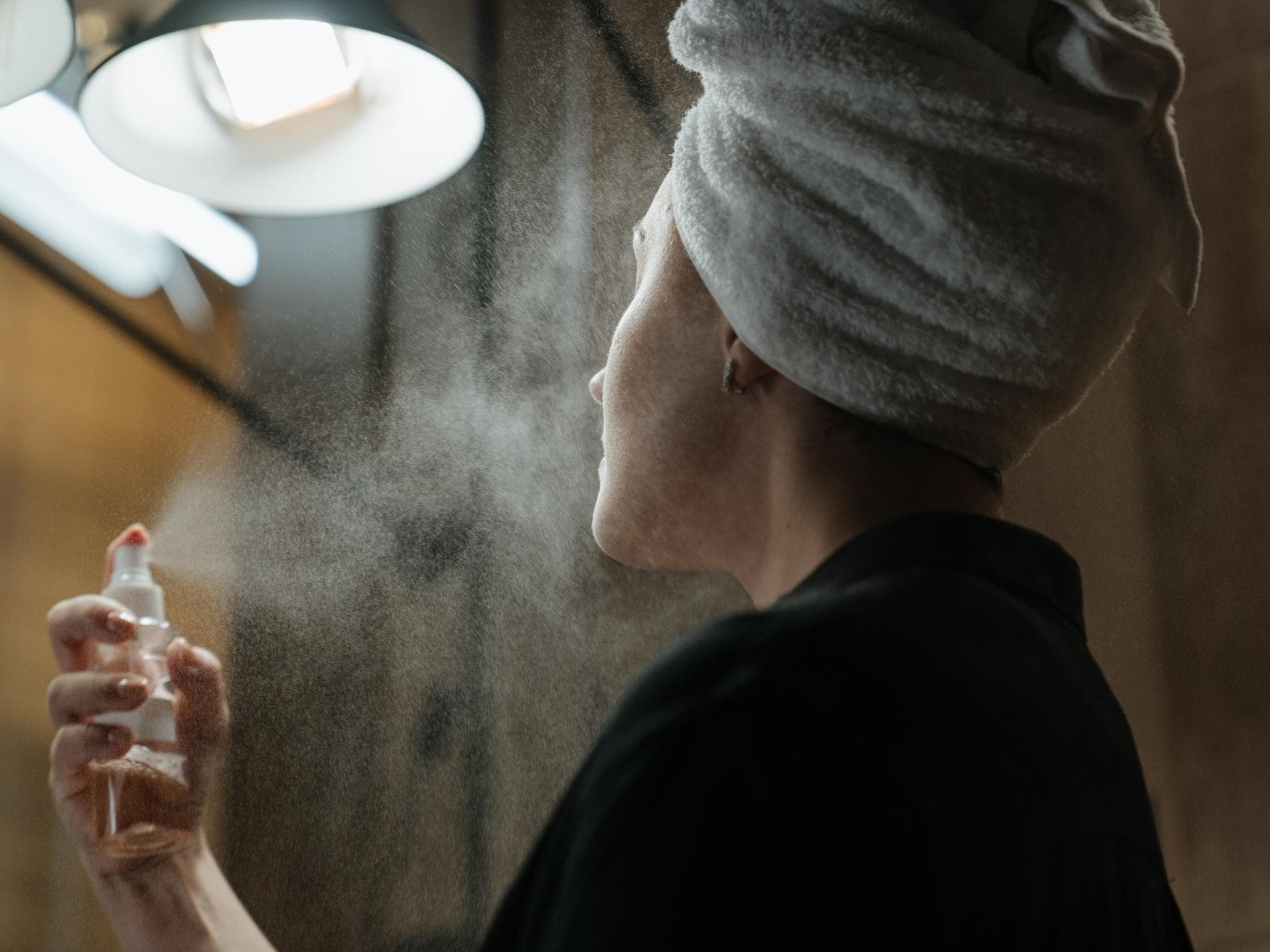 Frau benutzt Gesichtsspray