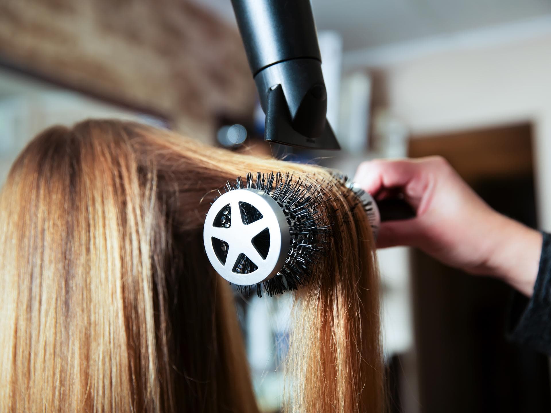 Frau werden die Haare auf einer Rundbürste geföhnt