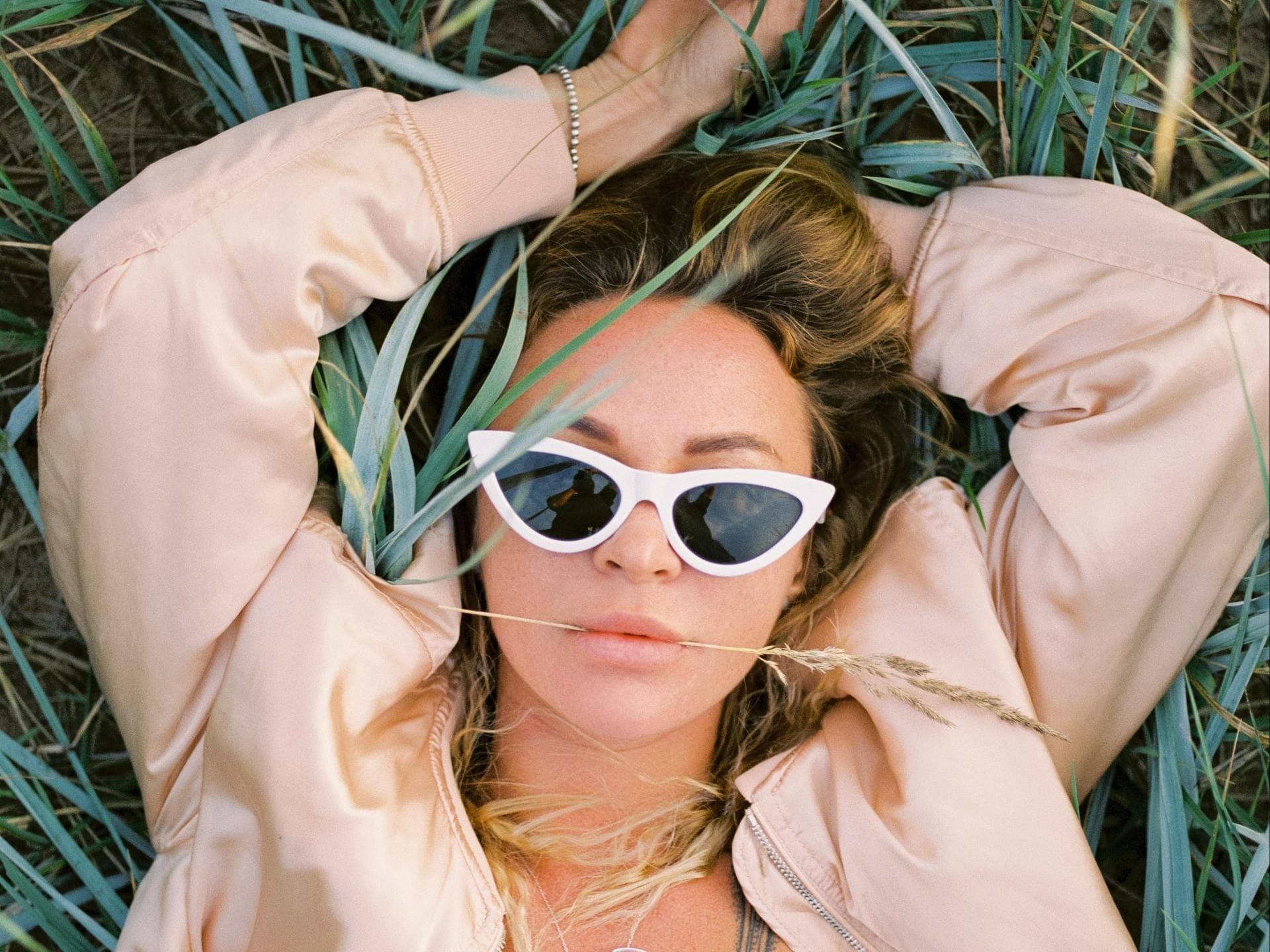Frau mit Sonnenbrille liegt im Gras