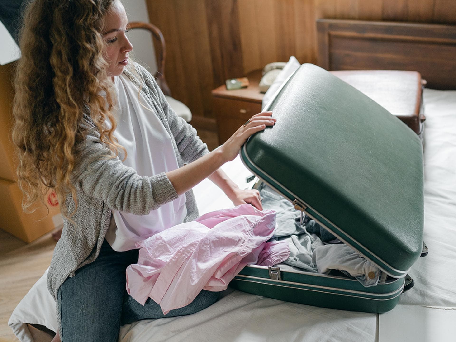 Frau packt Koffer auf dem Bett