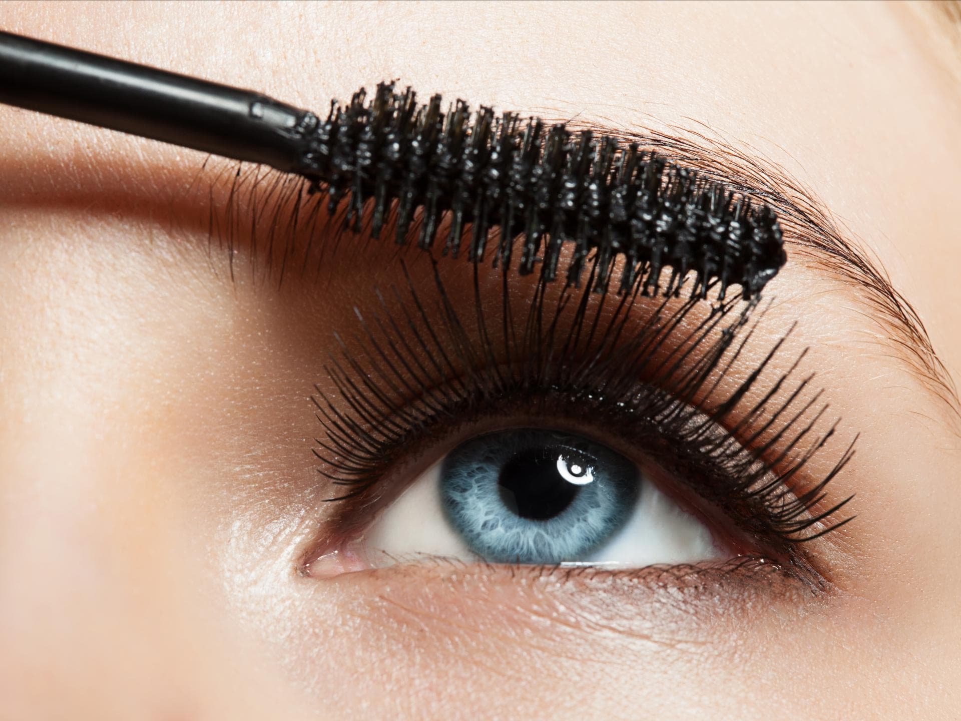 Frau schminkt sich mit Wimperntusche die Augen