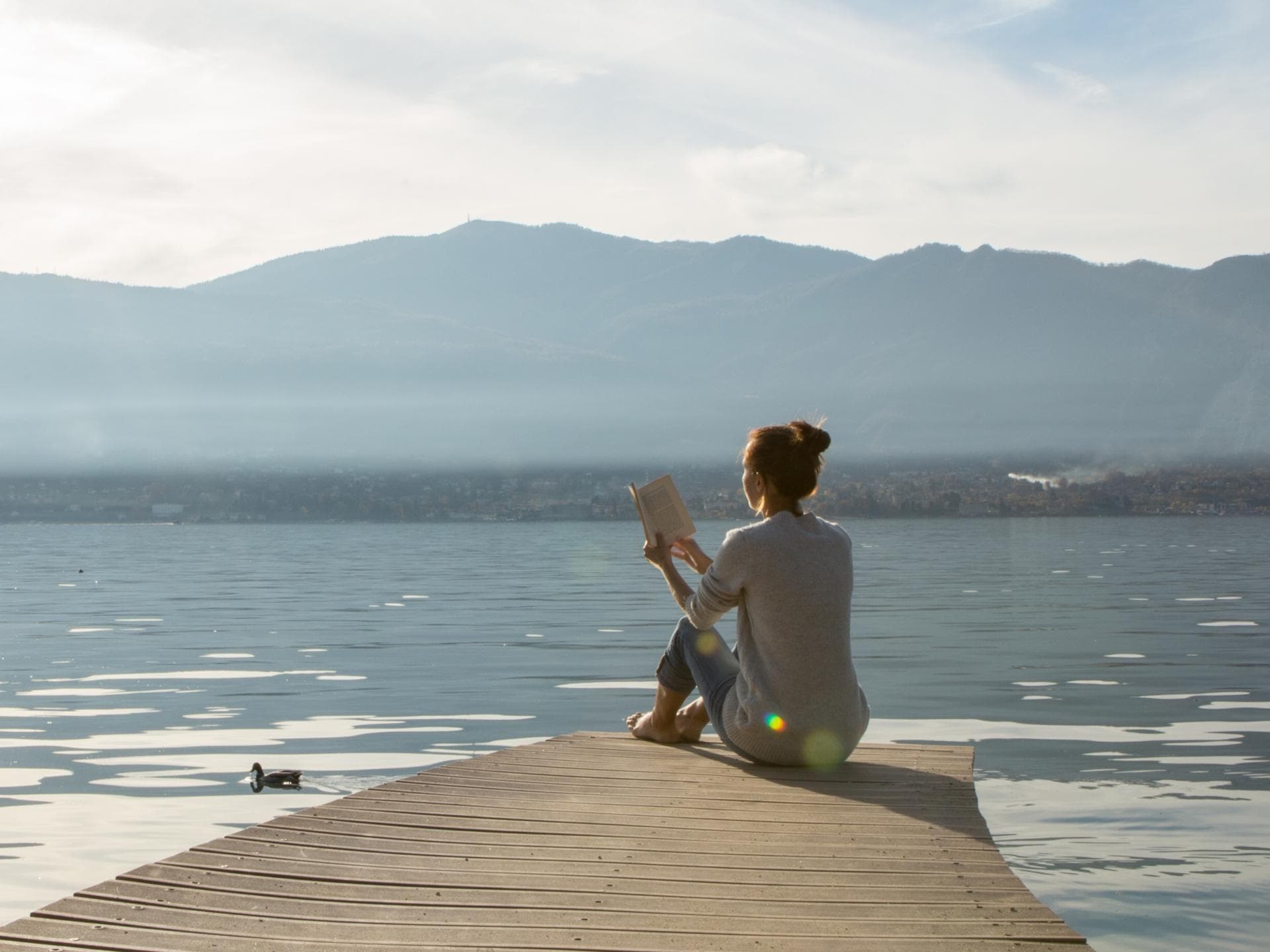 Frau sitzt nuit Buch am See