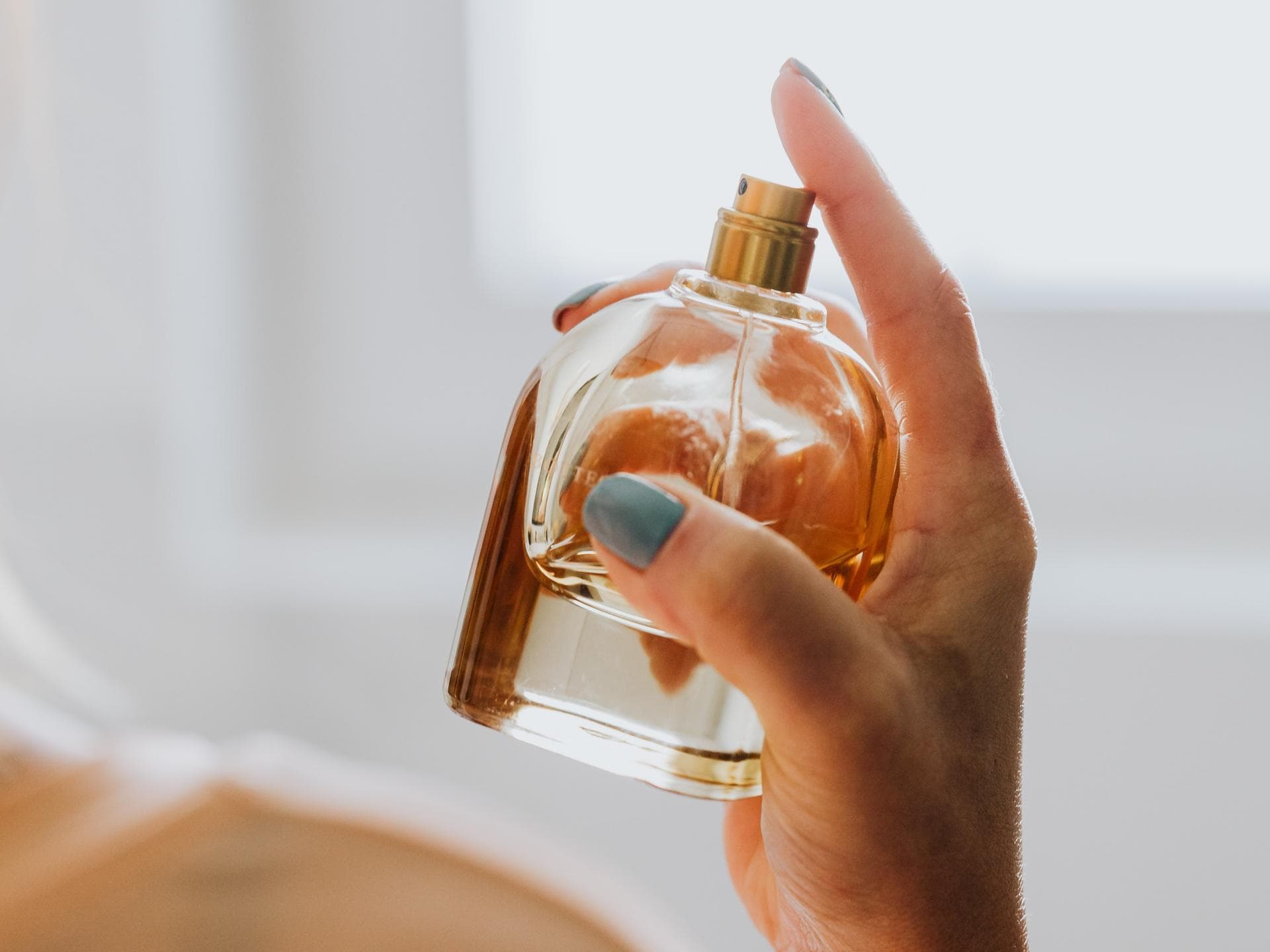 Frau hält Parfumflacon in der Hand