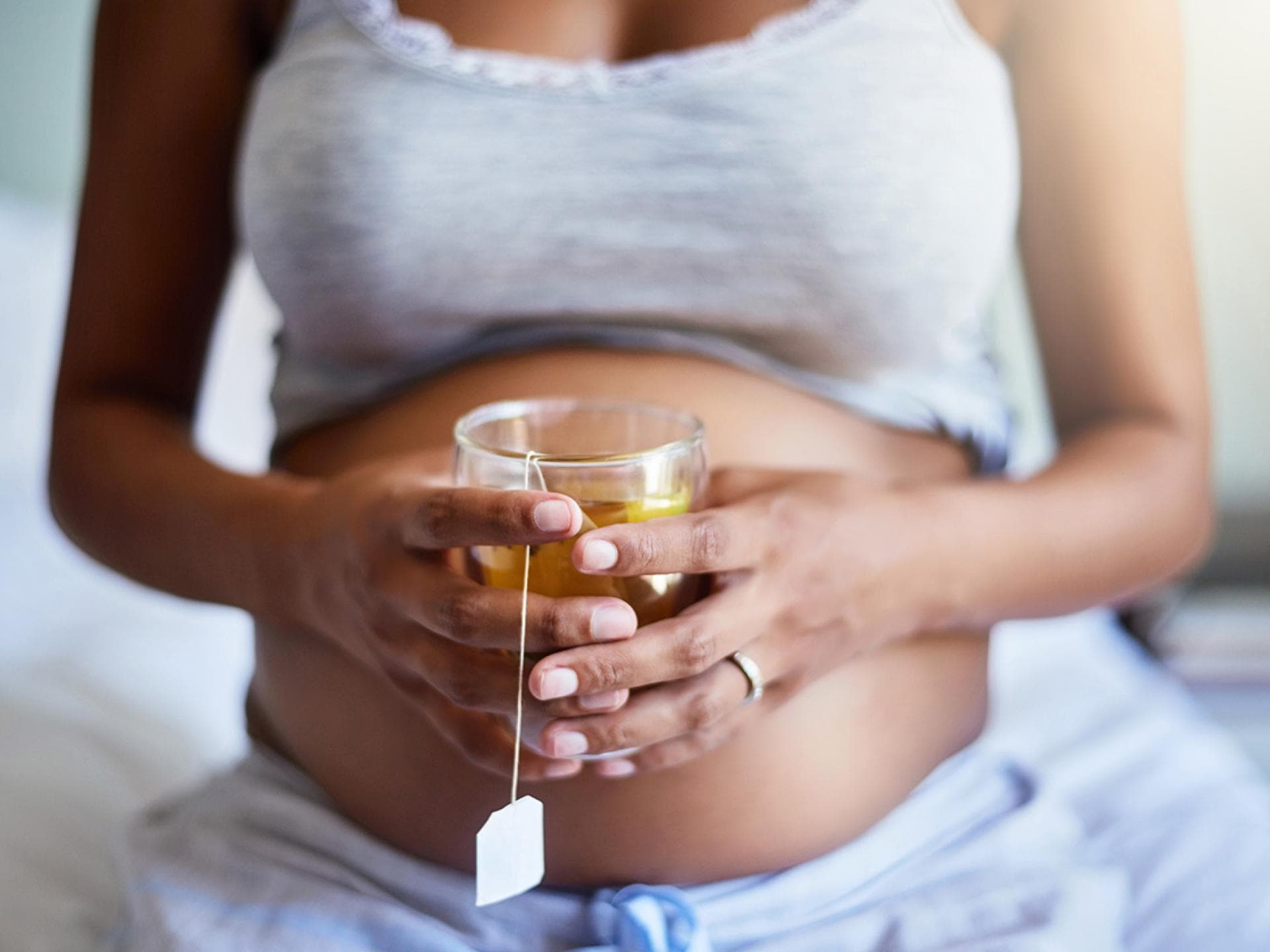 Schwangere Frau hält Kamillentee in der Hand