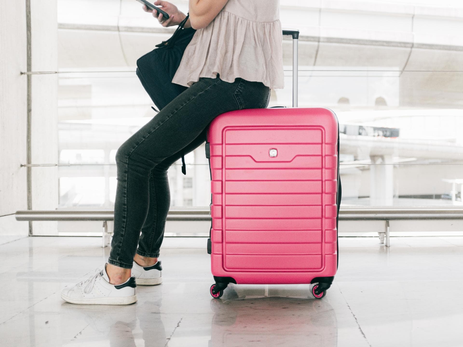 Person sitzt auf pinkem Koffer