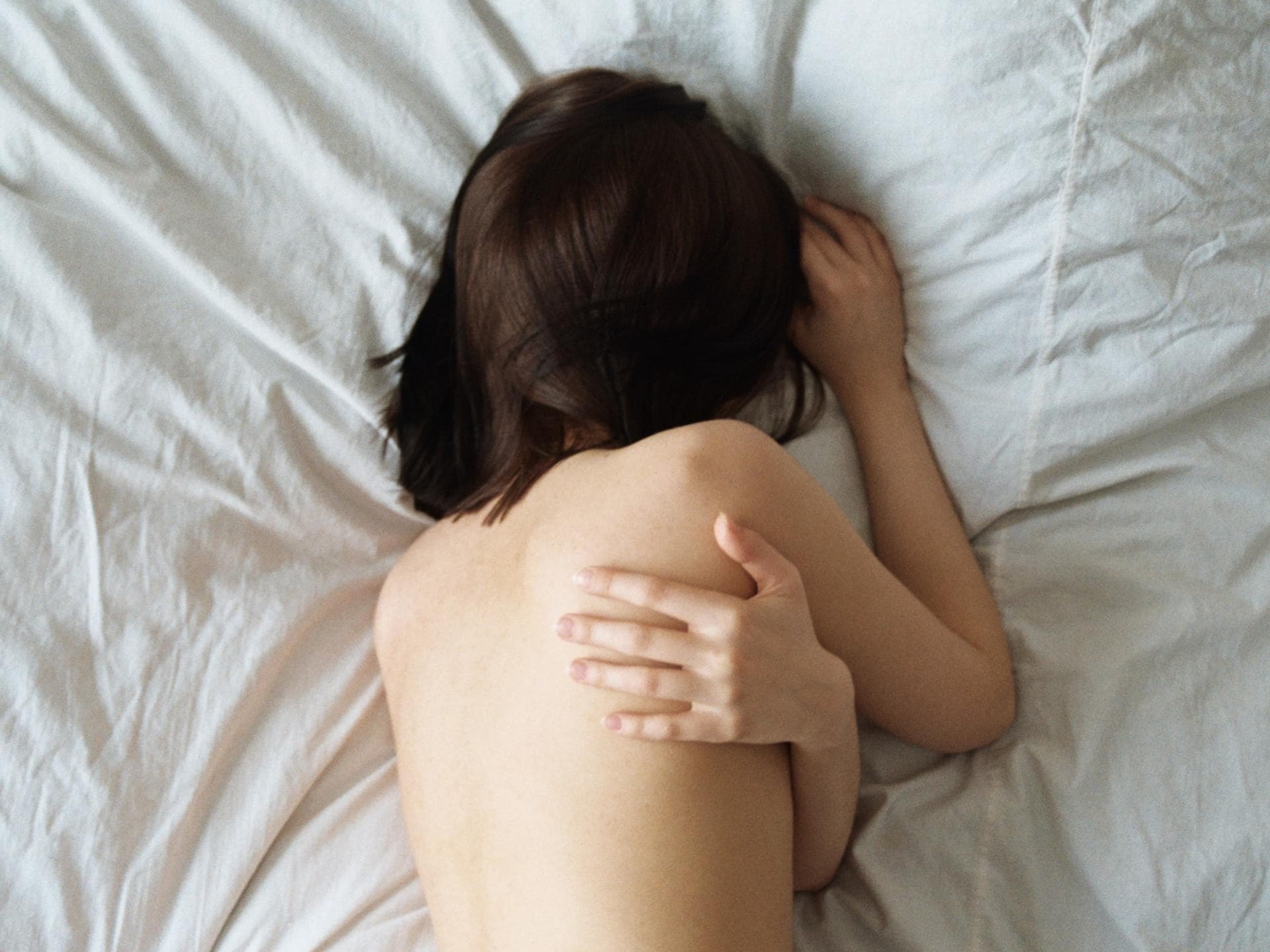 Frau schläft nackt im Bett
