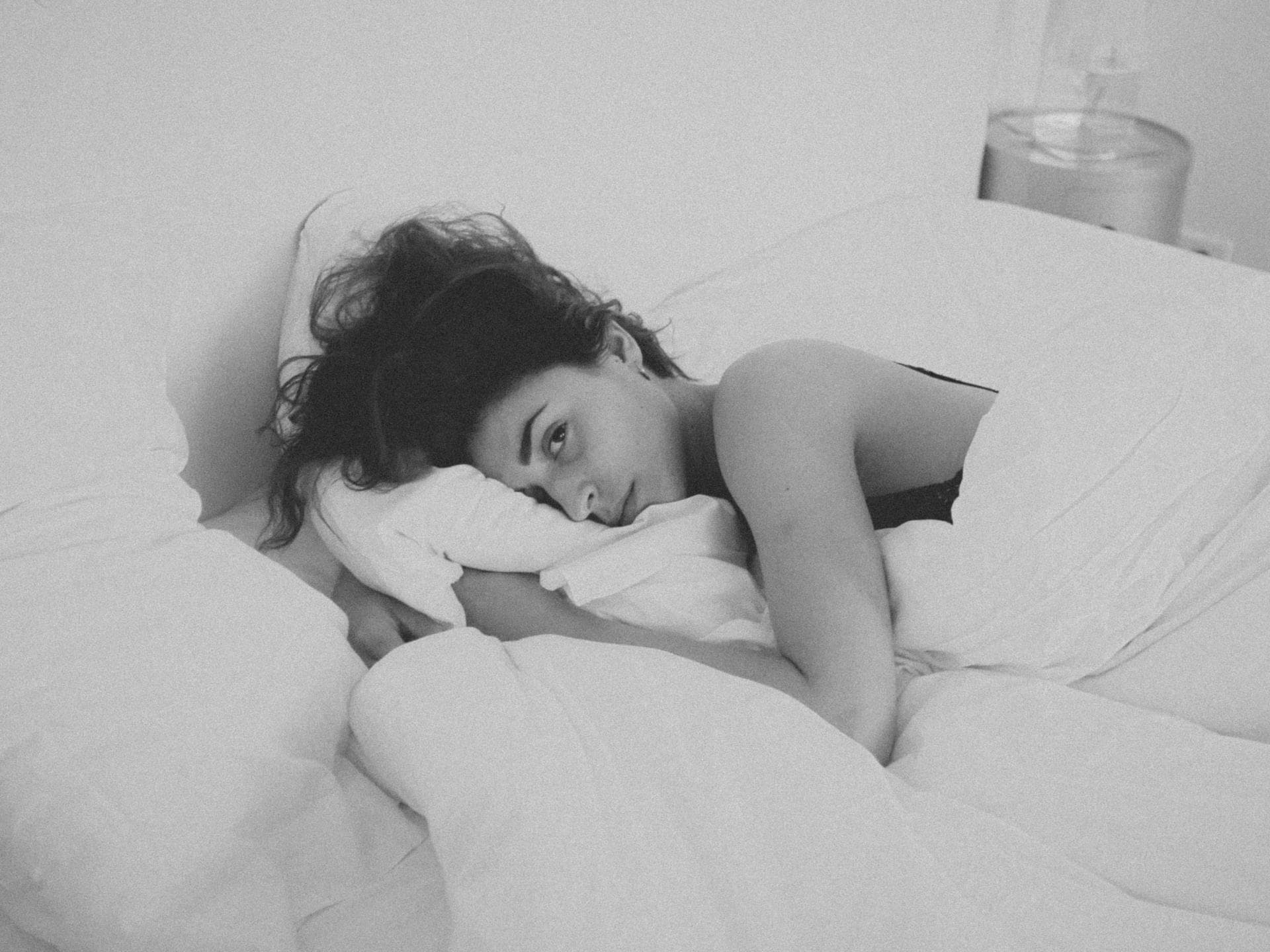 Frau liegt traurig im Bett