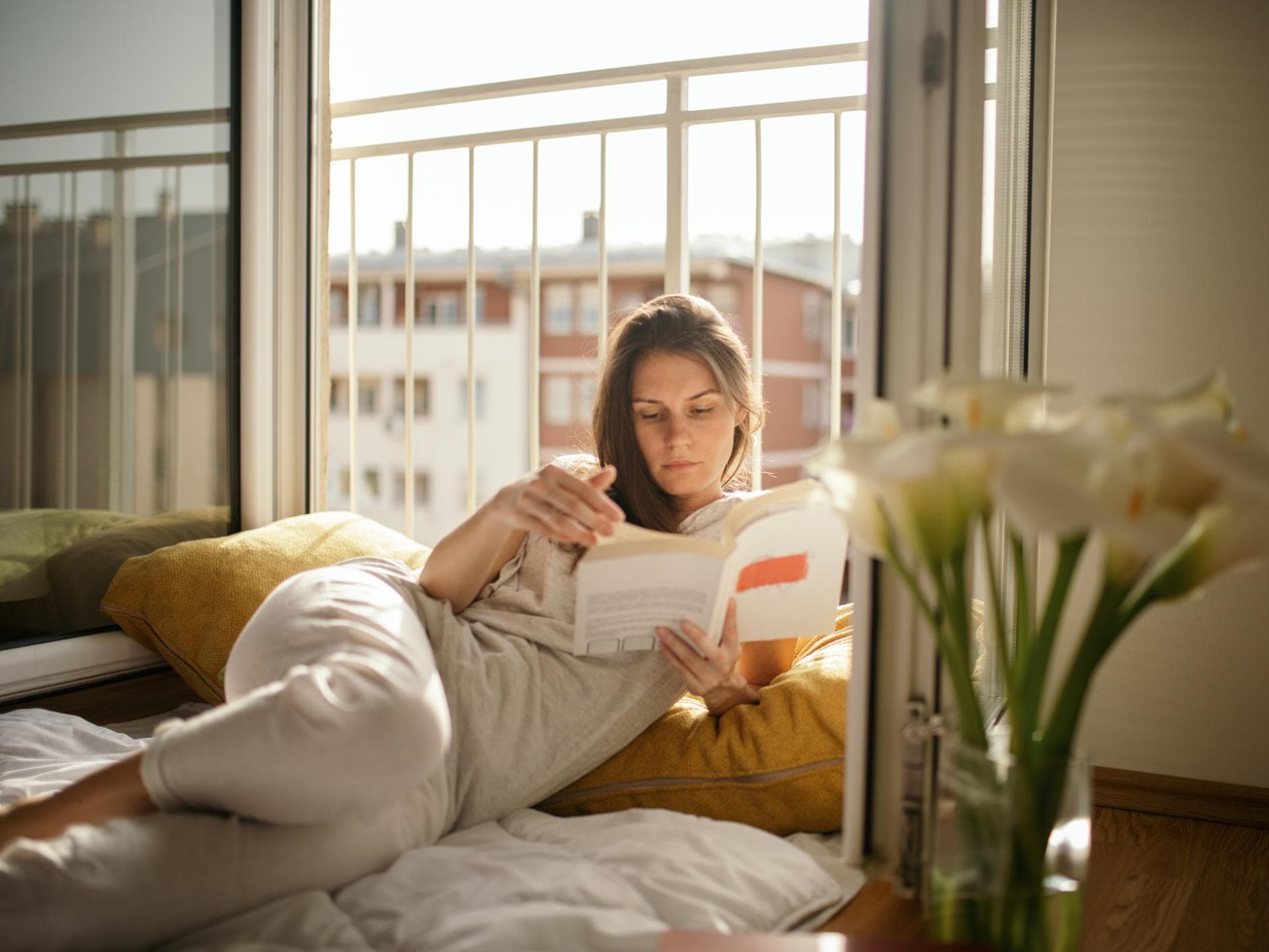 Frau liest Buch am Fenster