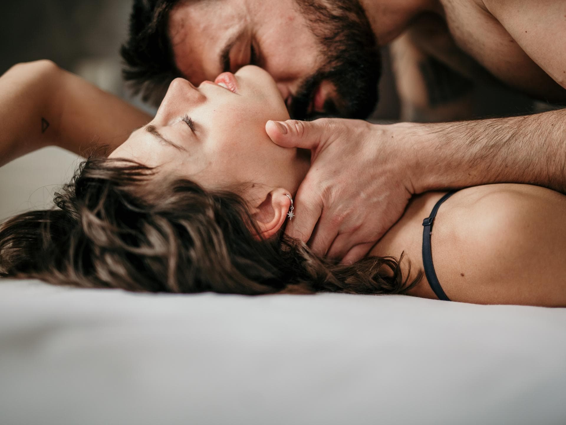 Mann küsst Hals der Frau im Bett
