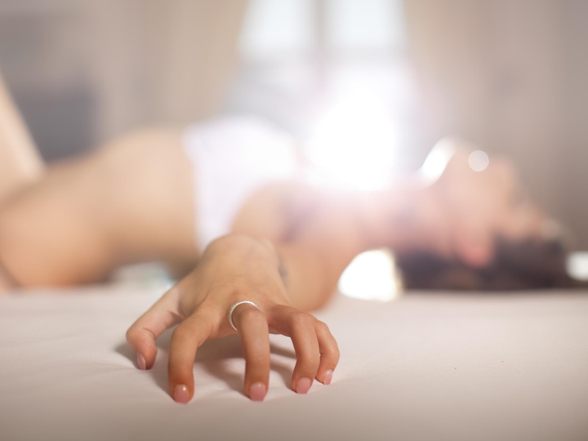 Frau liegt in Unterwäsche auf dem Bett