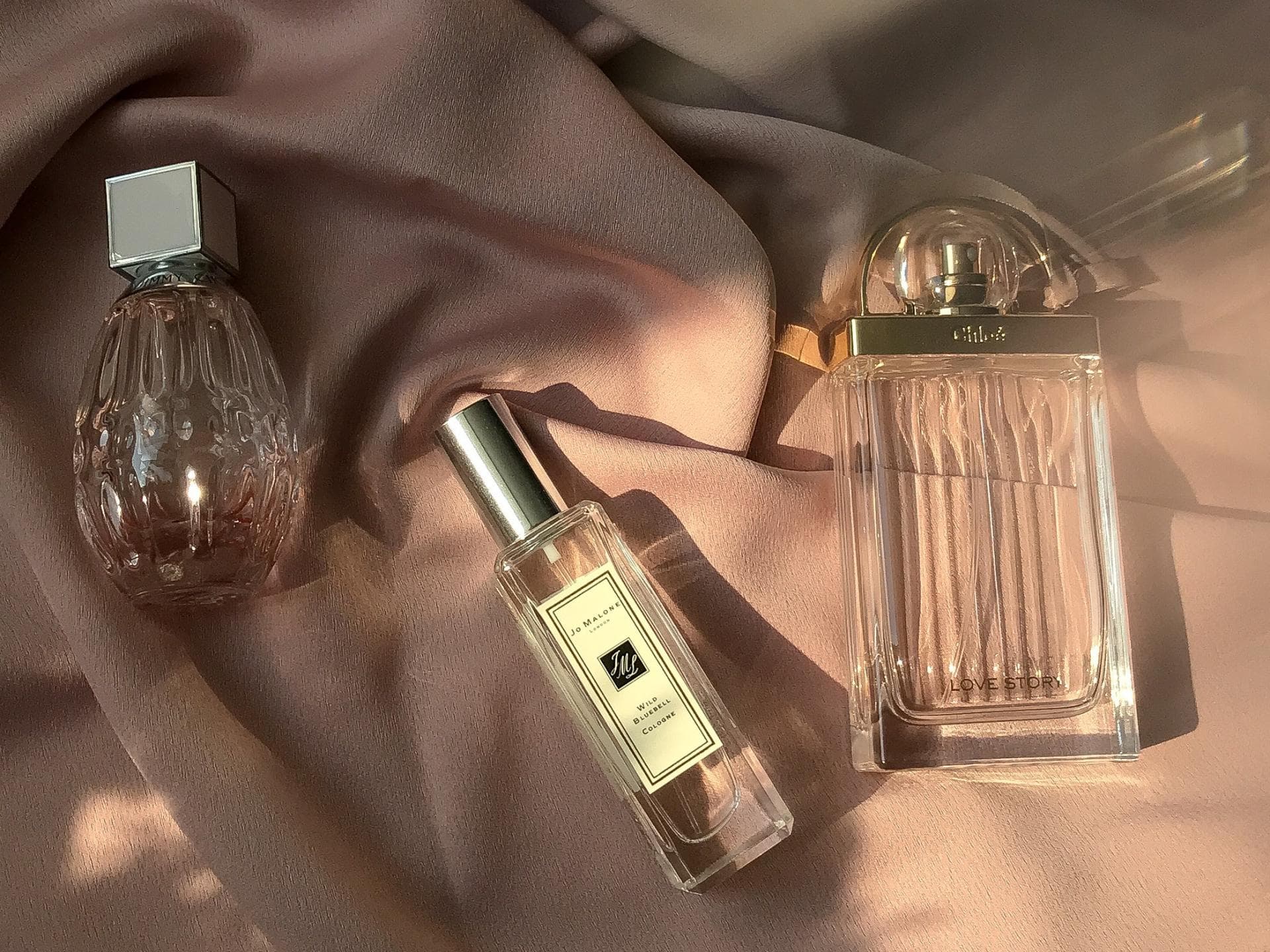 drei Parfums liegen auf einem Tuch