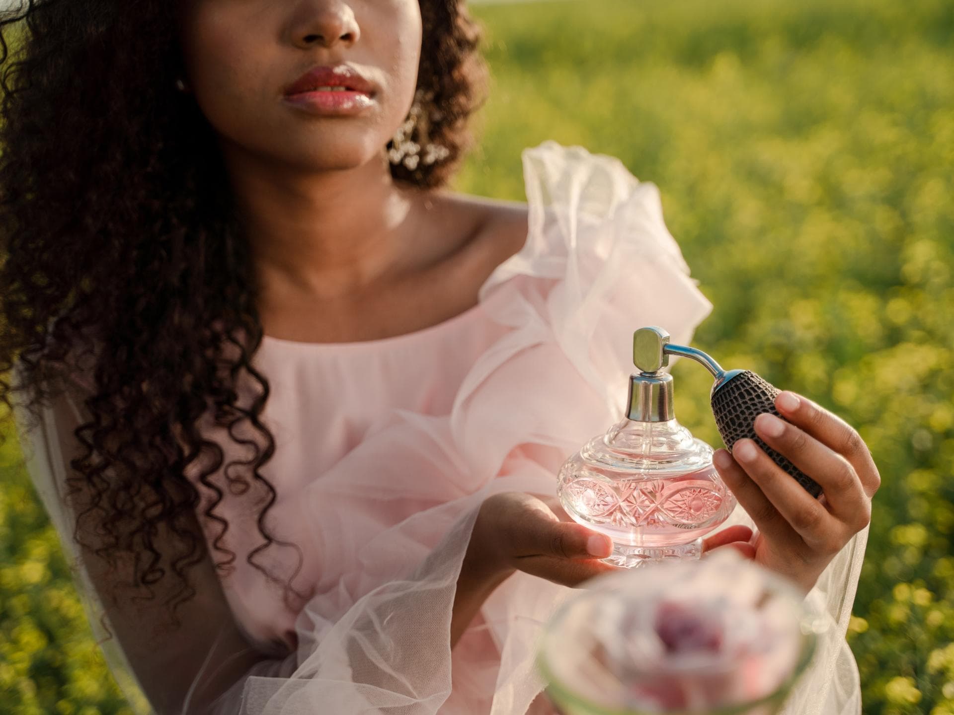 Frau hält rosa Parfum Flakon in der Hand