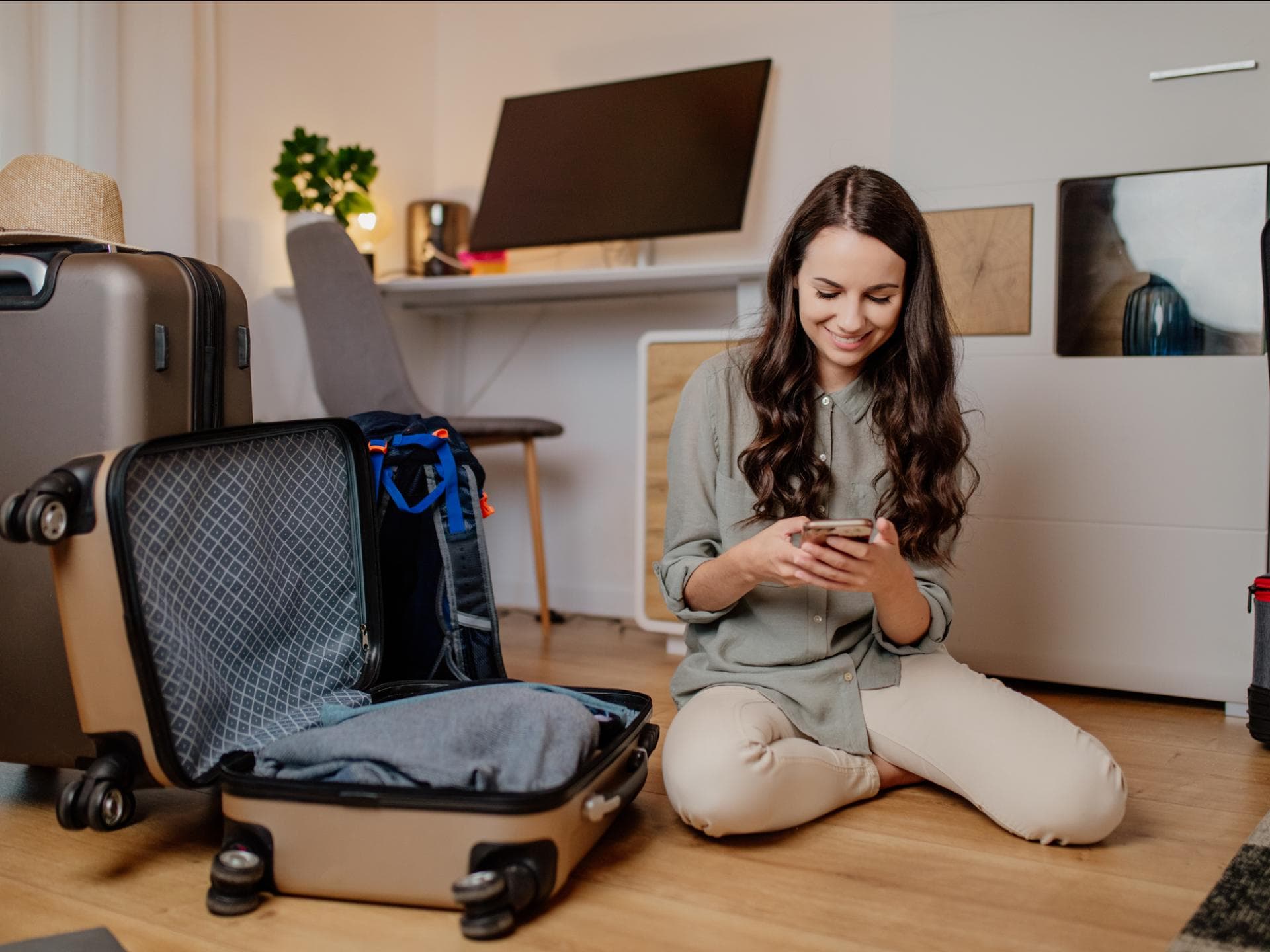 Urlaubsvorbereitung To-Do-Liste für Zuhause Frau sitzt auf dem Boden mit gepackten Koffern