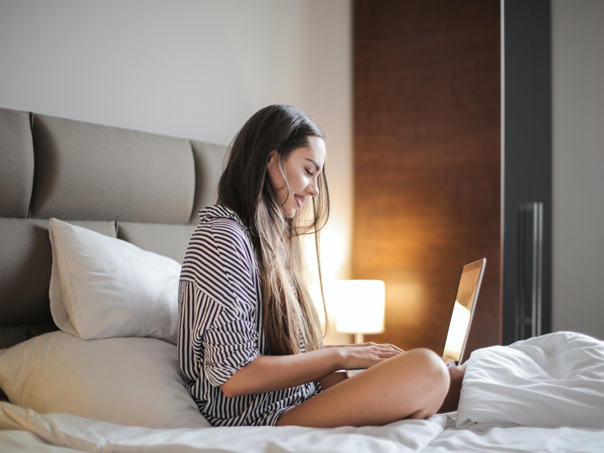 Junge Frau am Laptop im Bett
