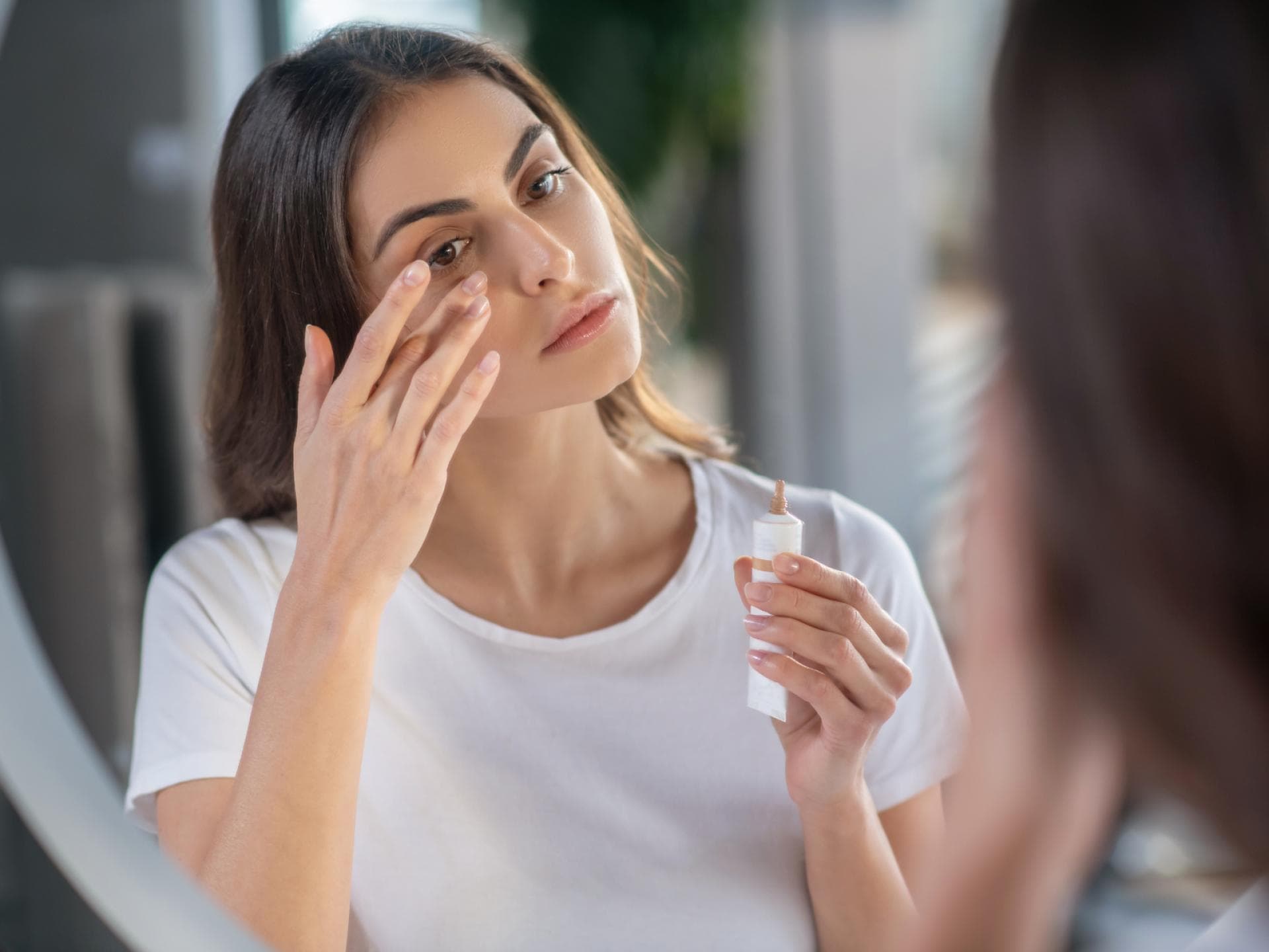 Frau deckt Augenringe mit Concealer ab