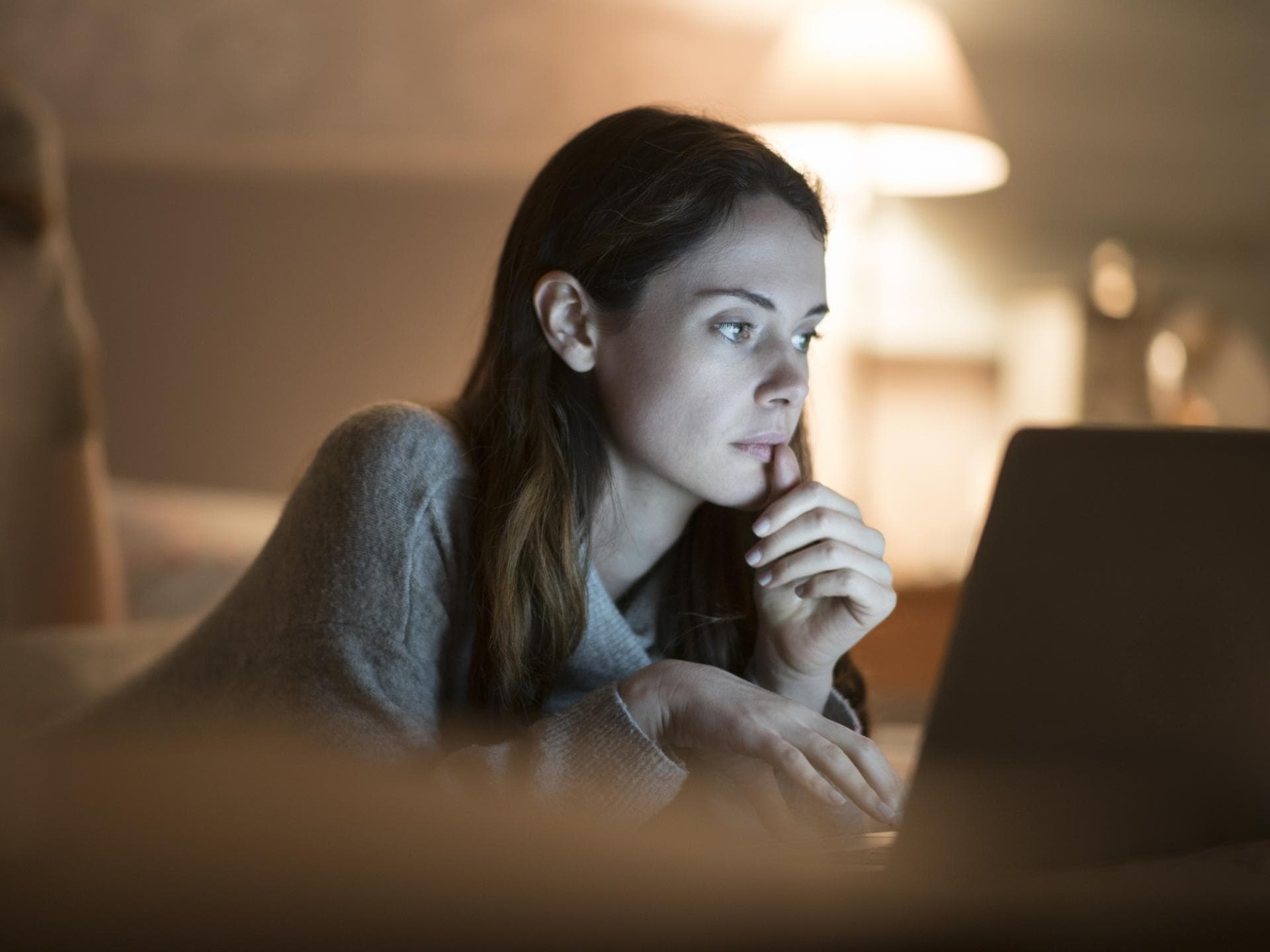 Junge Frau abends vor Laptop im Bett 
