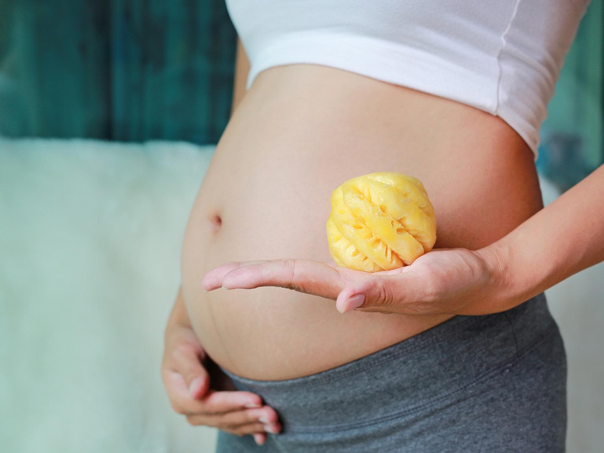 Schwangerer Bauch und Ananas