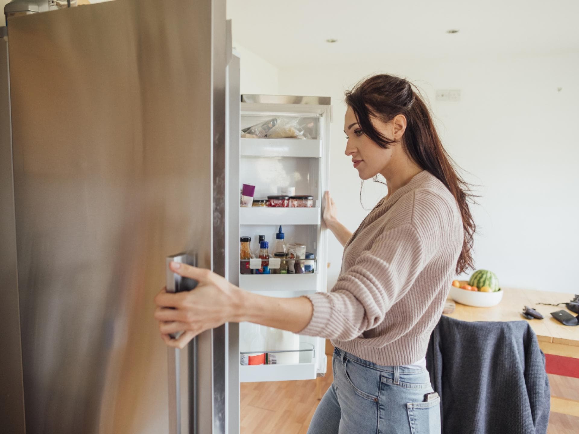 Frau schaut in den Kühlschrank