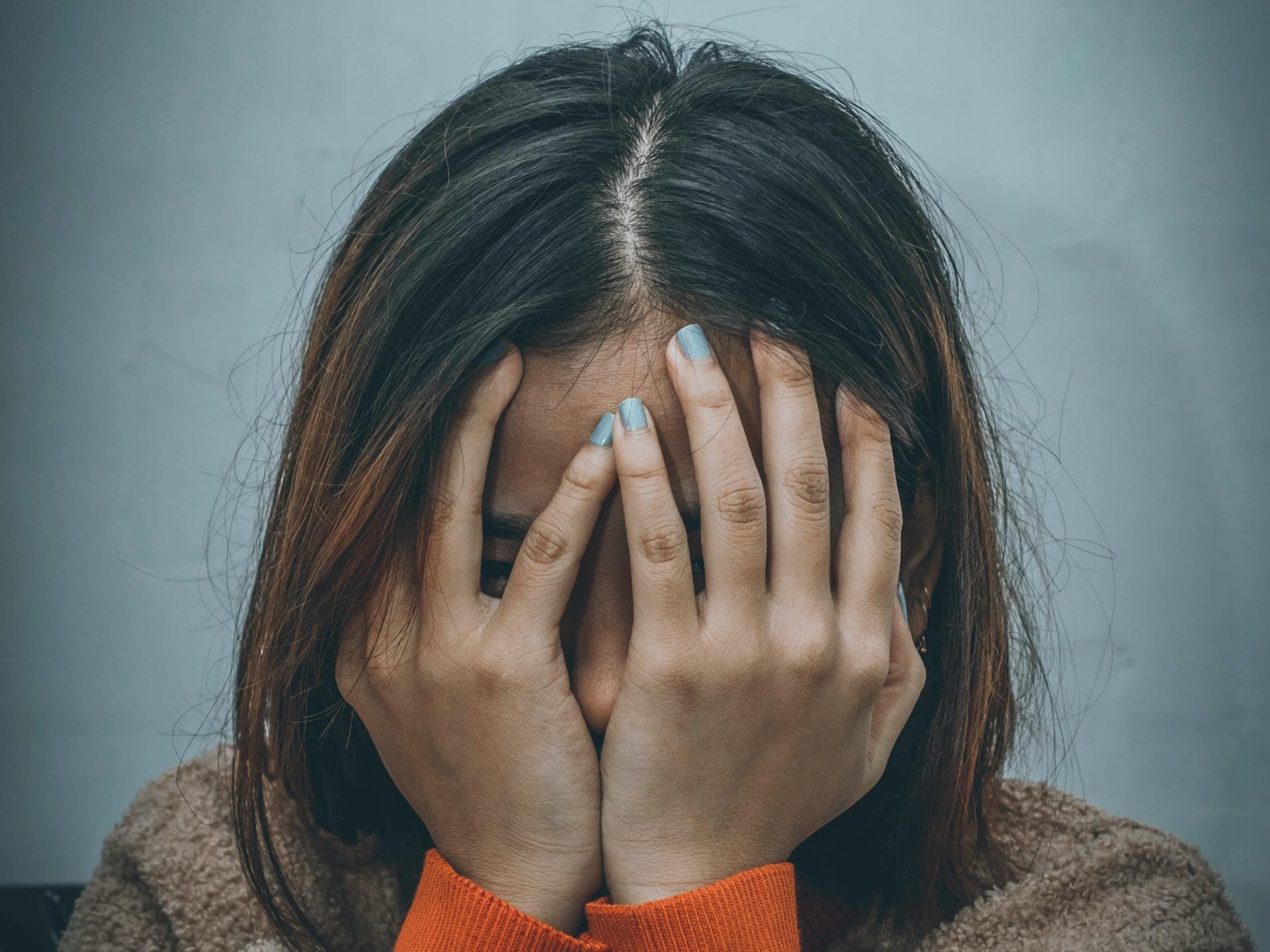 Frau hält Hände vors Gesicht