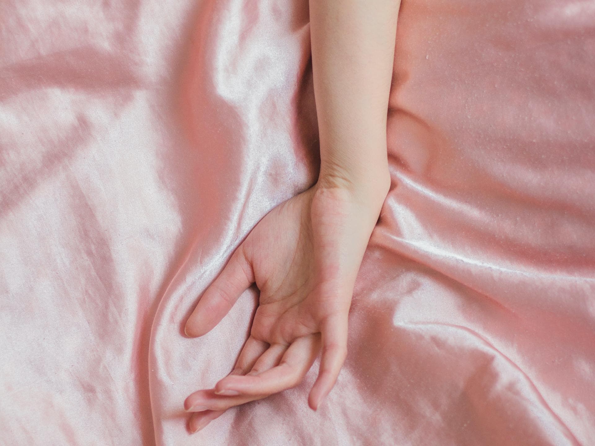 Hand auf Seidenbettwäsche
