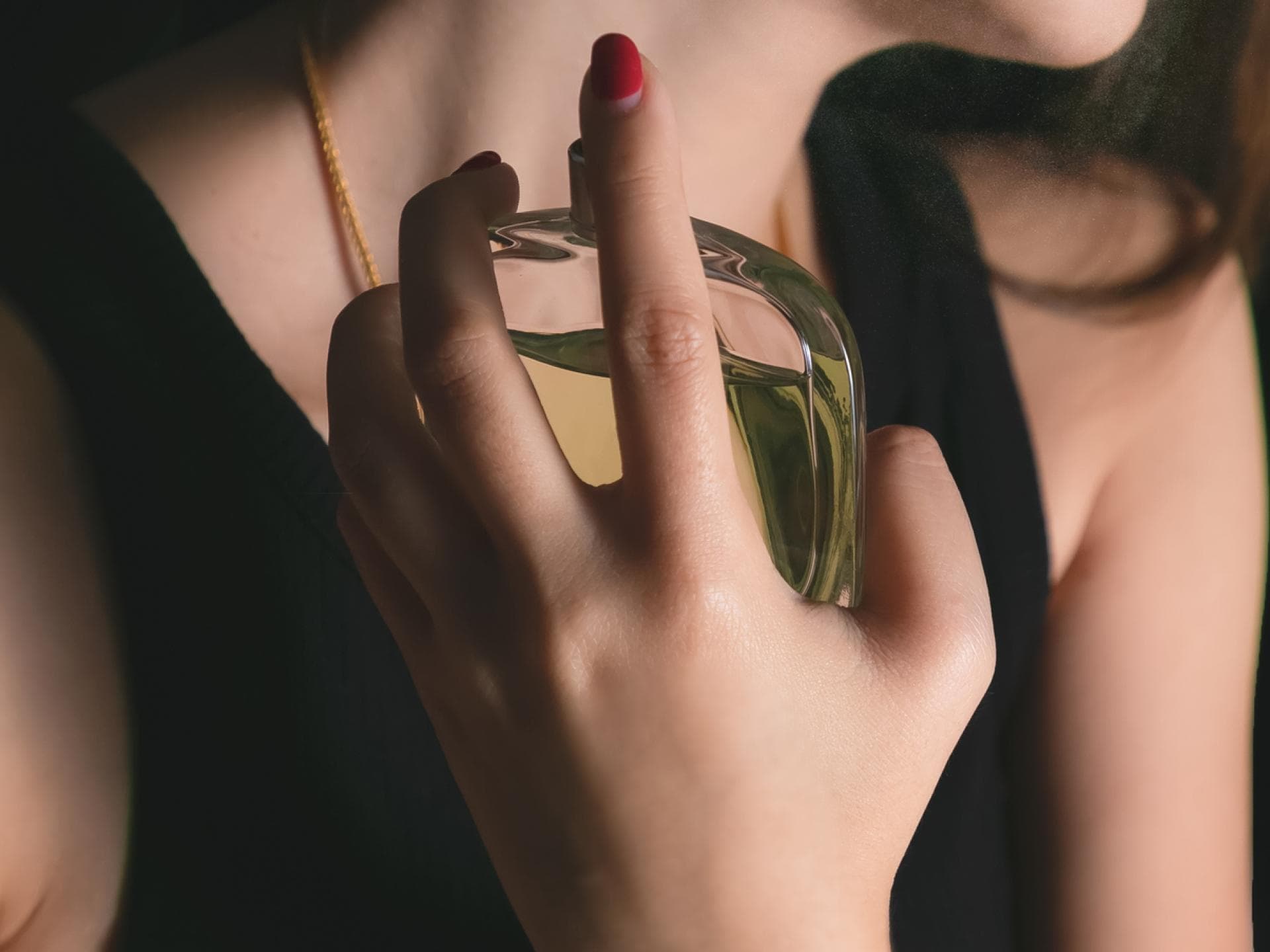 Frau sprüht Parfum auf 