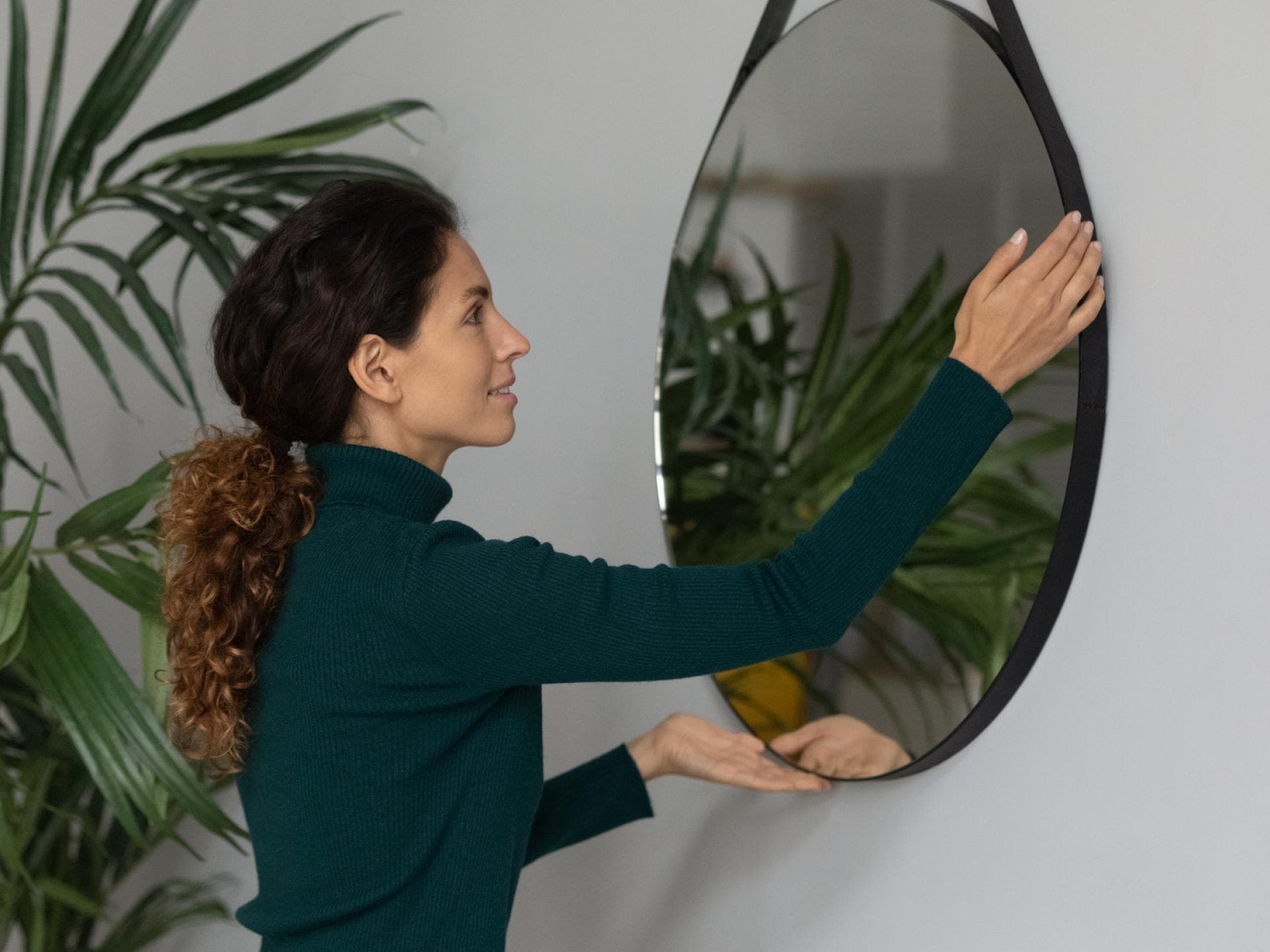 Frau hängt Spiegel an die Wand