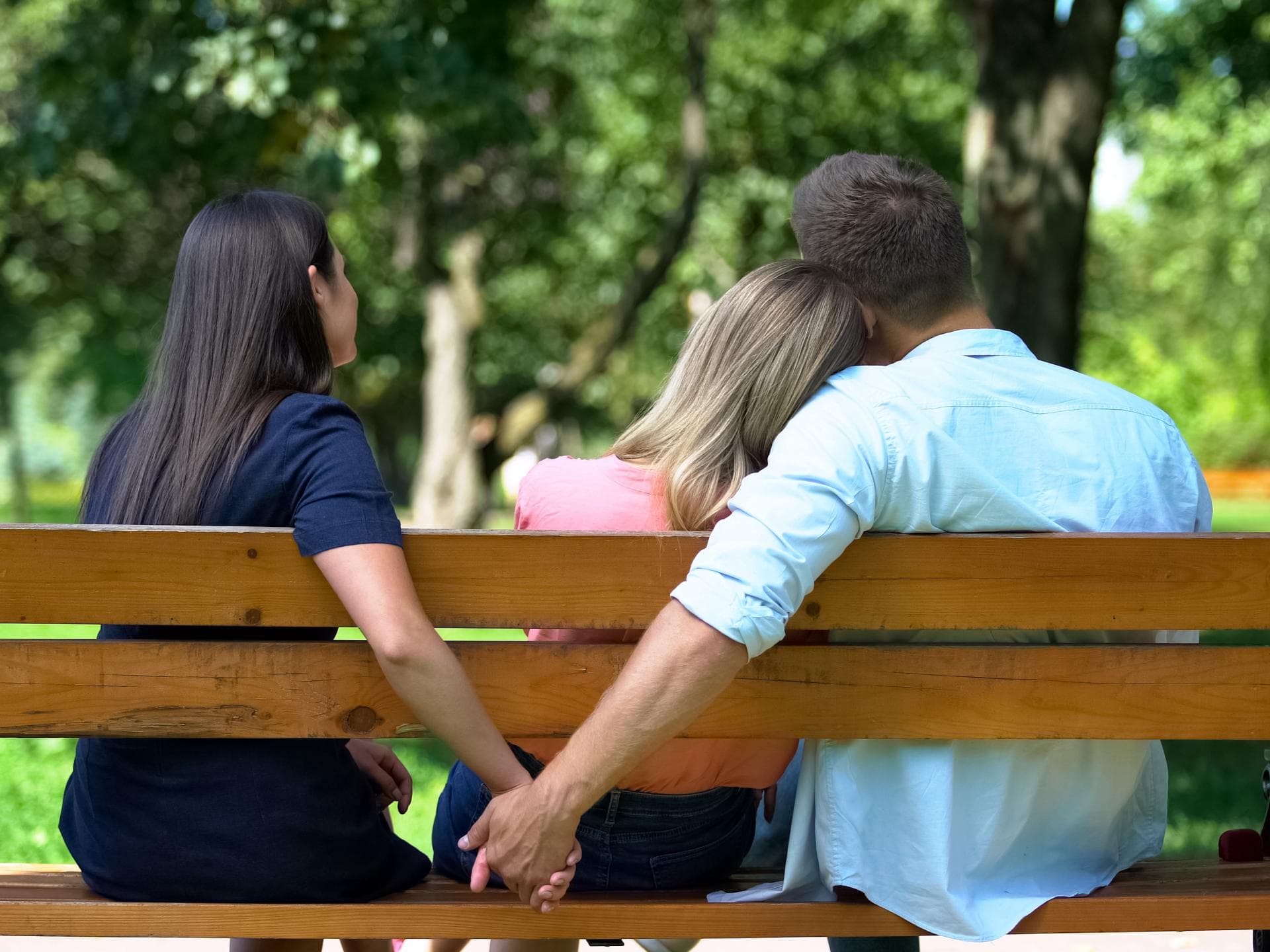 Mann hält Hand mit einer Frau hinter einer Bank