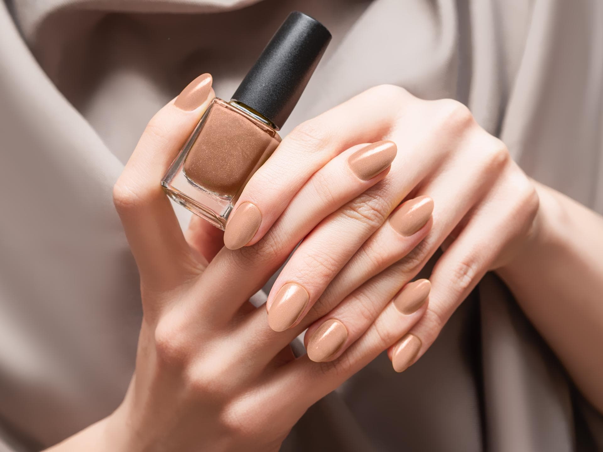 Die Toffee Nails von Selena Gomez sind der Nageltrend im Herbst Person hält braunen Nagellack