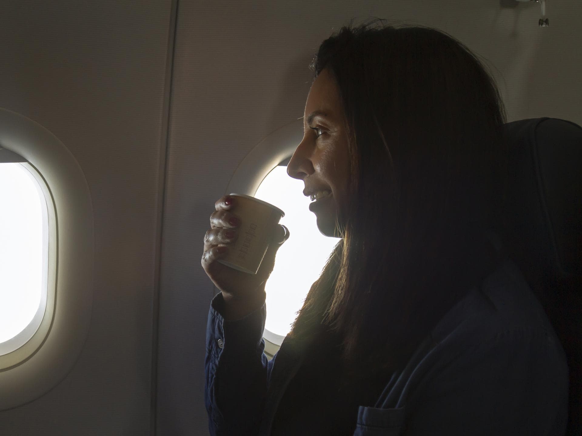 Frau trinkt Kaffee im Flugzeug