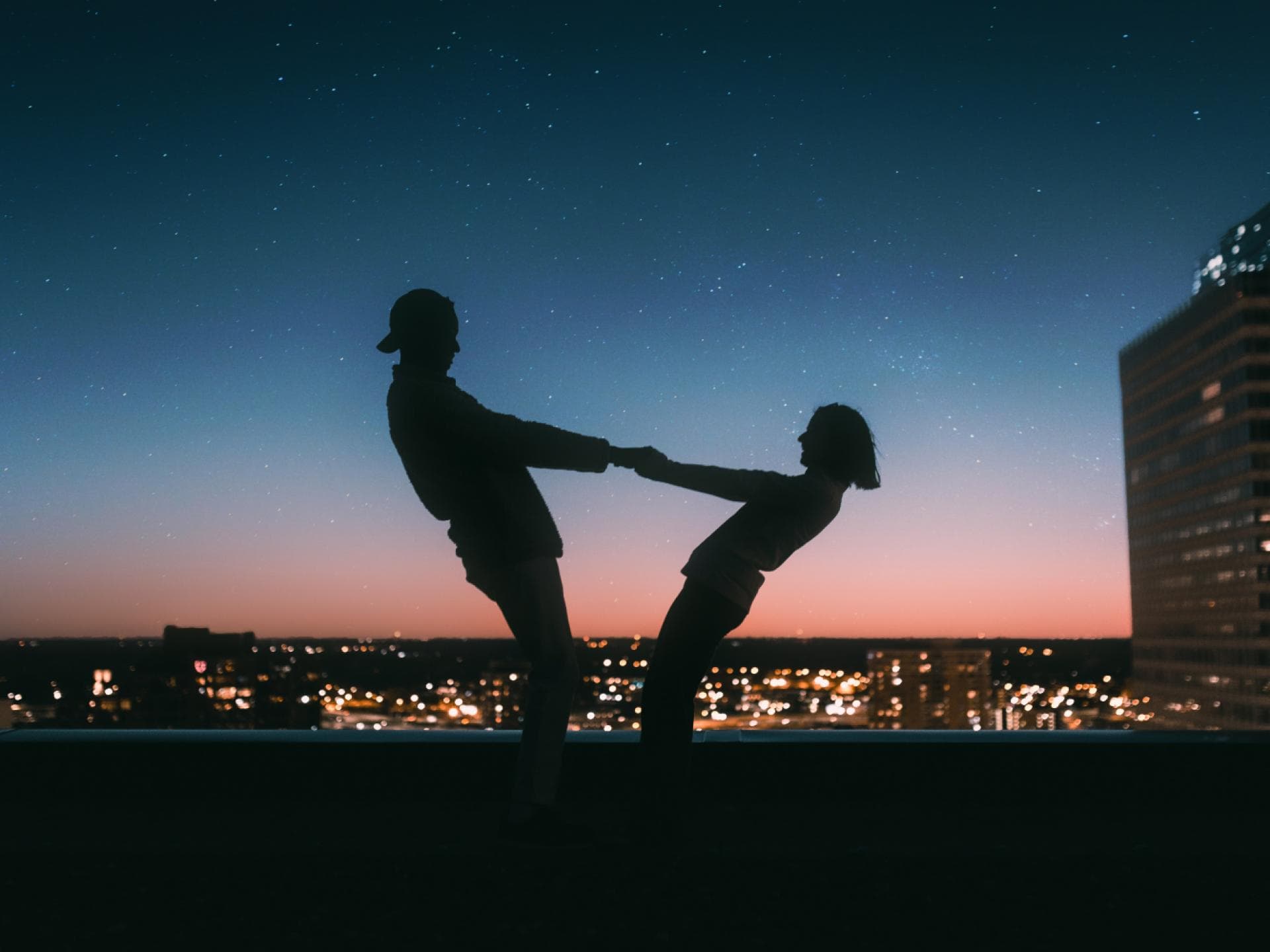 Silhouette eines Paares, das auf dem Dach ist und Händchen hält
