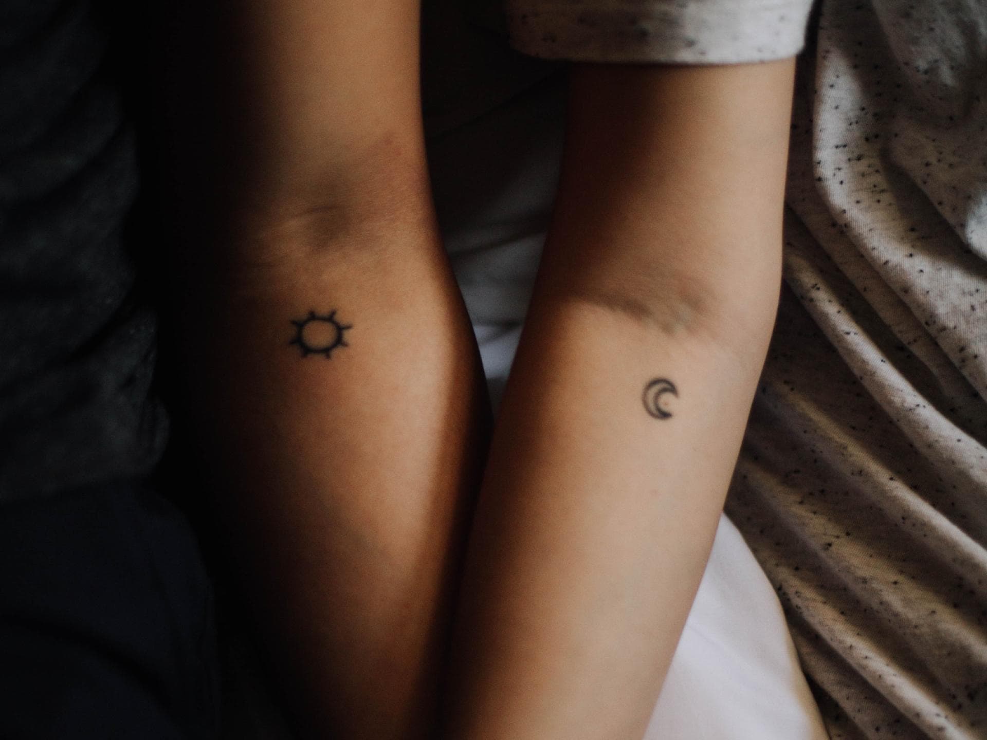 zwei Arme mit kleinen Tattoos Mond und Sonne
