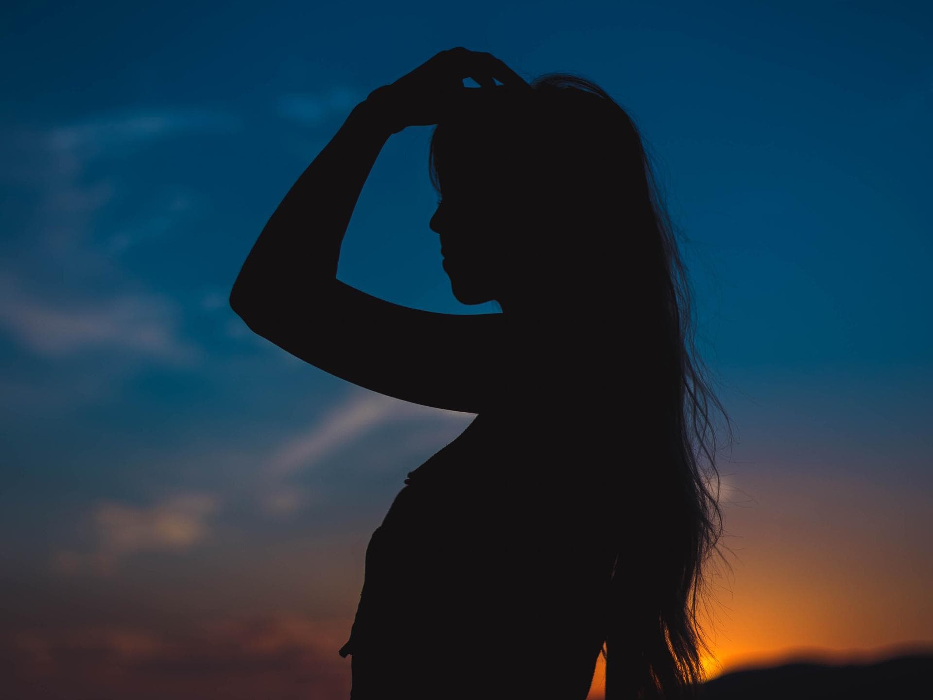 Pech-Sternzeichen der Woche Silhouette einer Frau mit langen Haaren in der Dämmerung