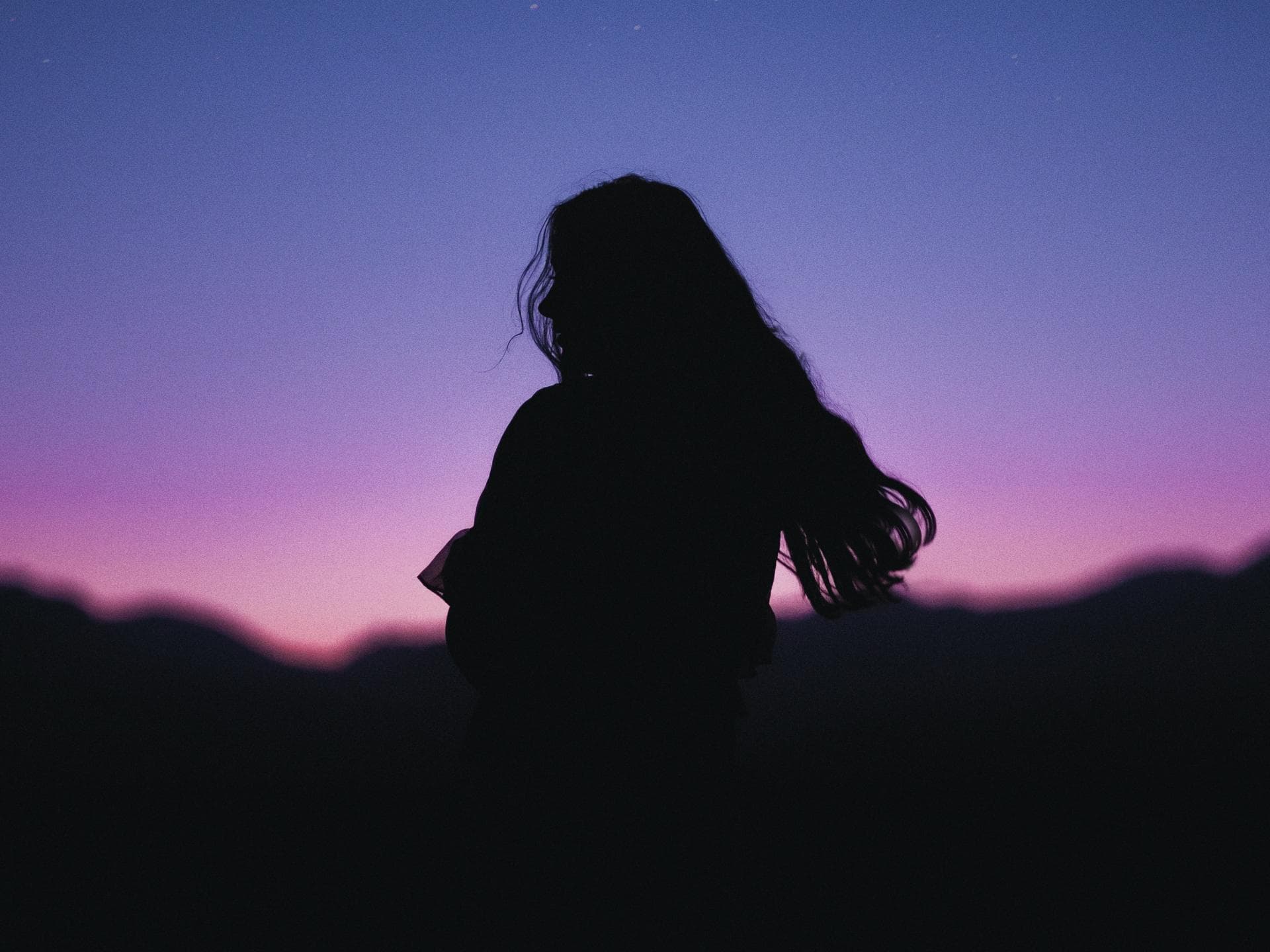 Horoskop heute: Dein Tageshoroskop am 28. November 2024 Silhouette einer Frau mit langen Haaren in der Nacht