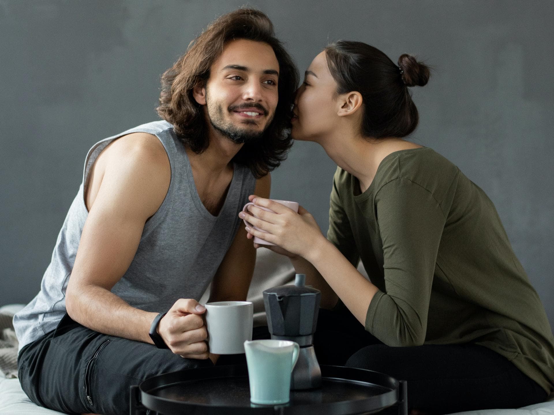 Mann und Frau sitzen auf einem Bett und trinken Kaffee
