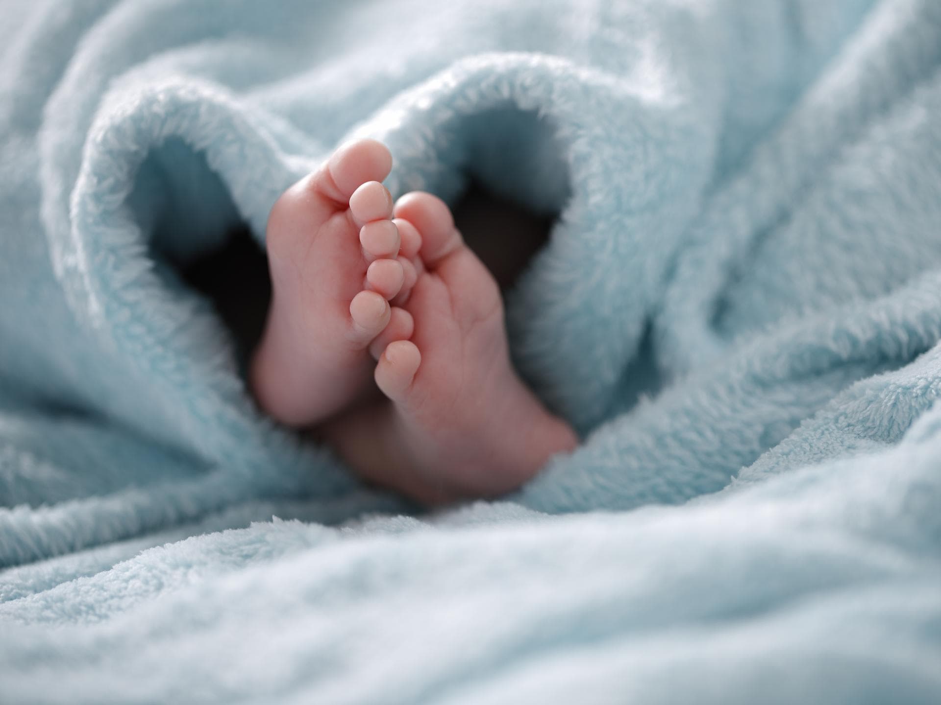 Babyfüße unter einer hellblauen Decke