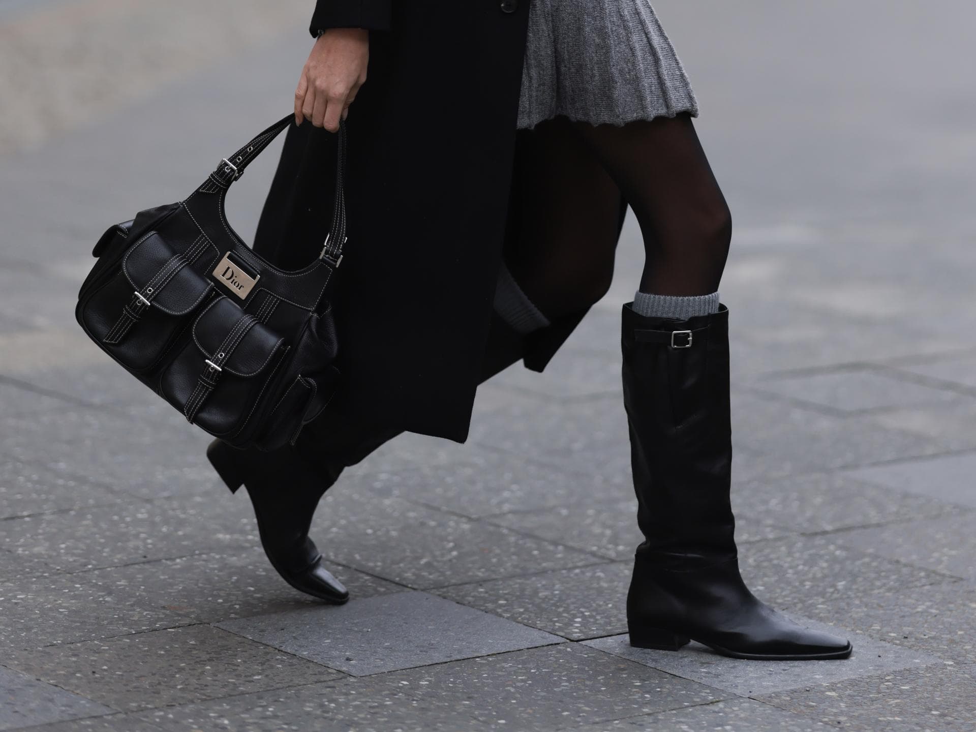 Frau trägt Stiefel und Dior-Tasche