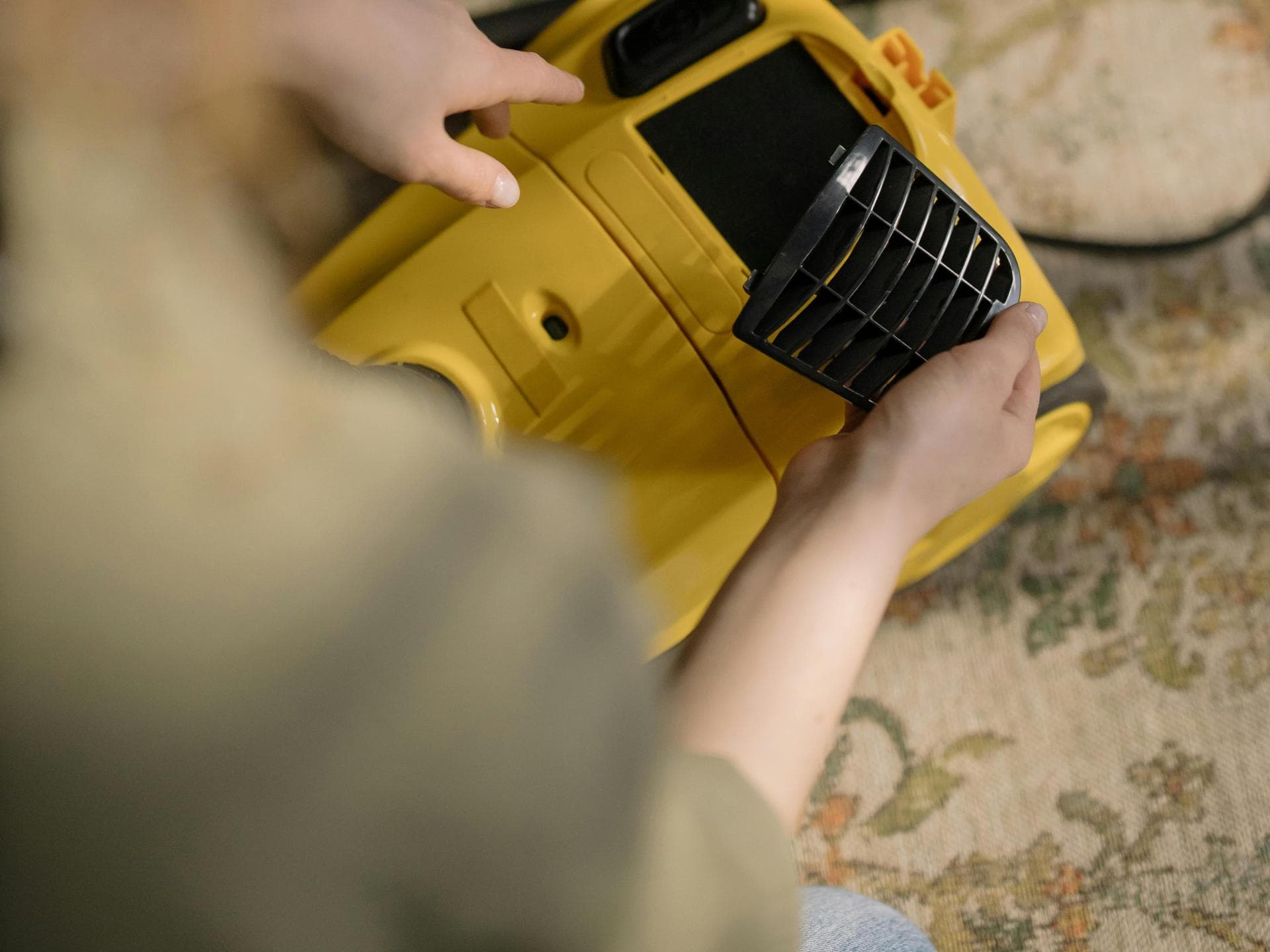 Junge Frau im grünen Shirt wechselt den Filter ihres Staubsaugers
