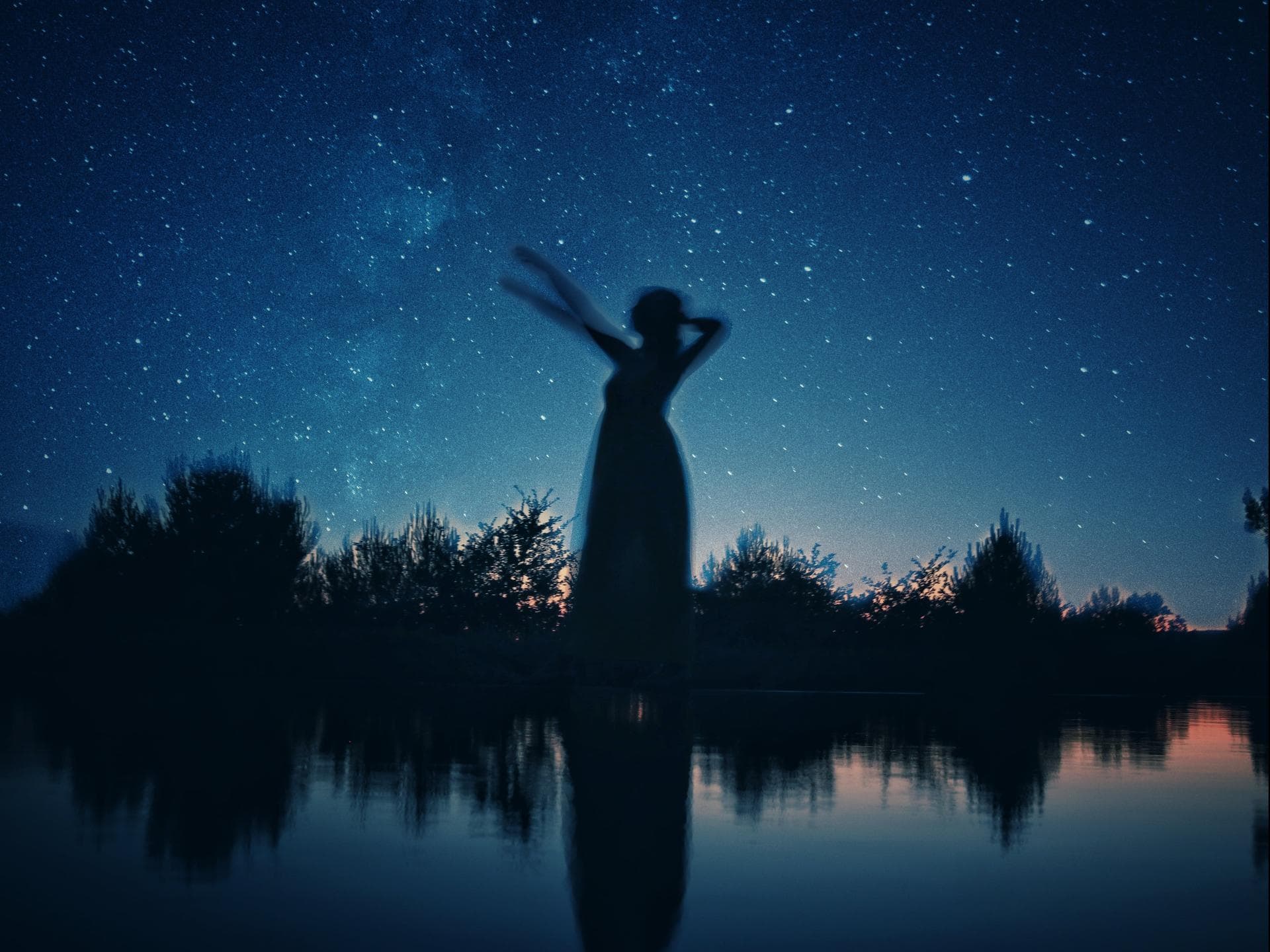 Schattenbild einer Frau an einem See in der Nacht