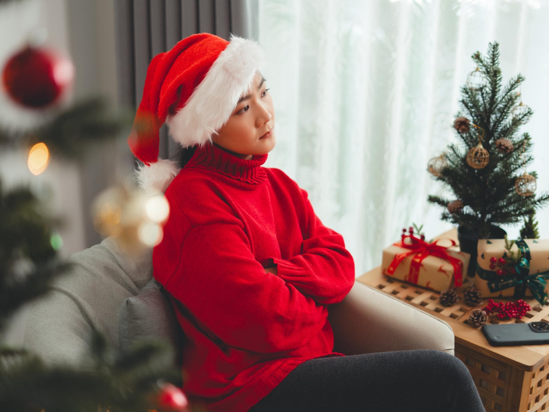 Frau mit Weihnachtsmütze sitzt auf dem Sofa
