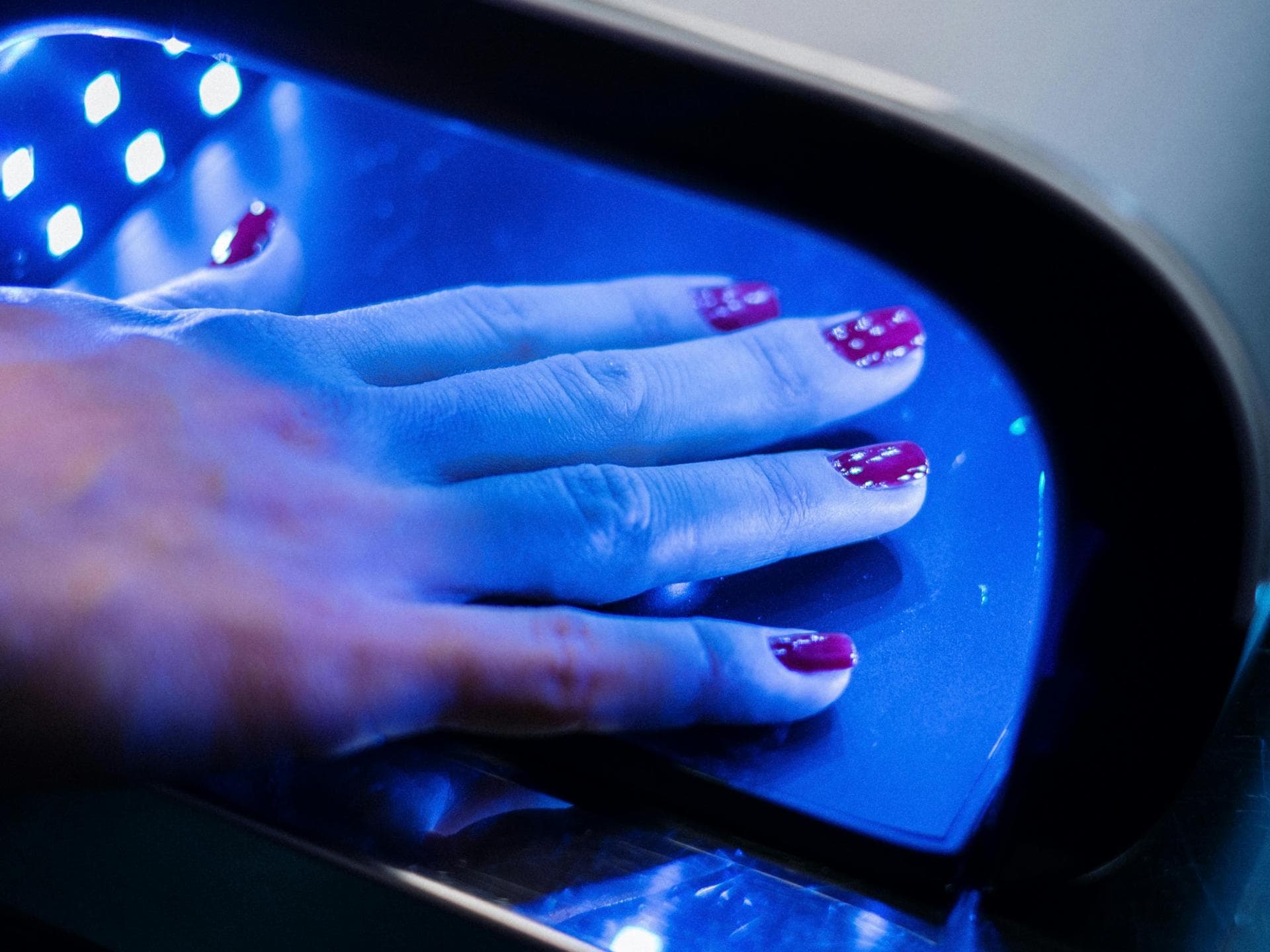 Weibliche Hand mit Nagellack unter UV-Lampe
