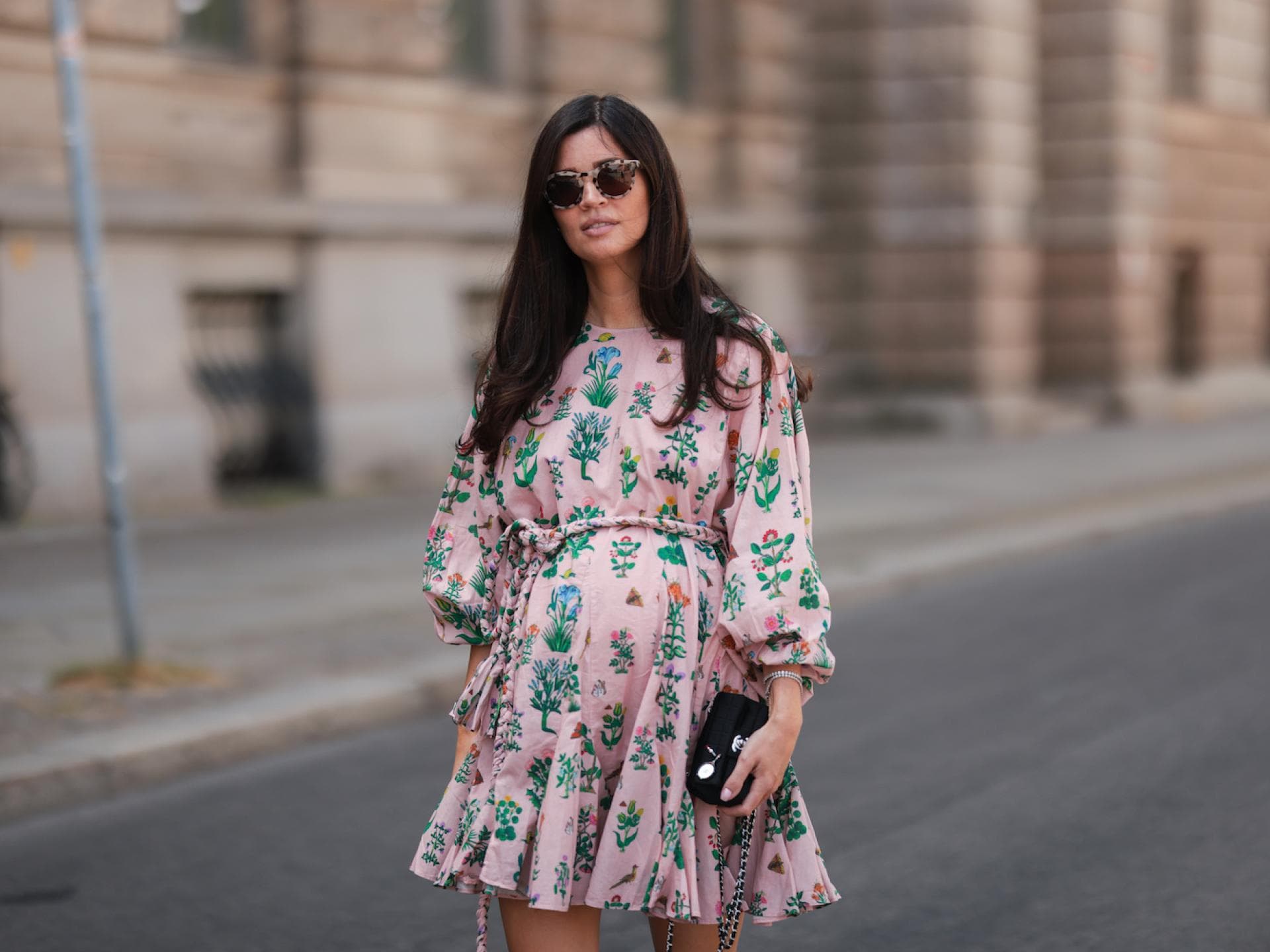 Schwangere Frau im rosanen Kleid mit Sonnenbrille
