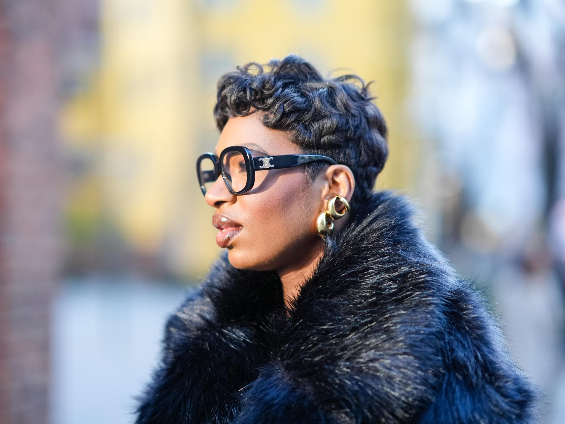 Bester Haarschnitt für Locken Frau trägt kurze Locken und Brille