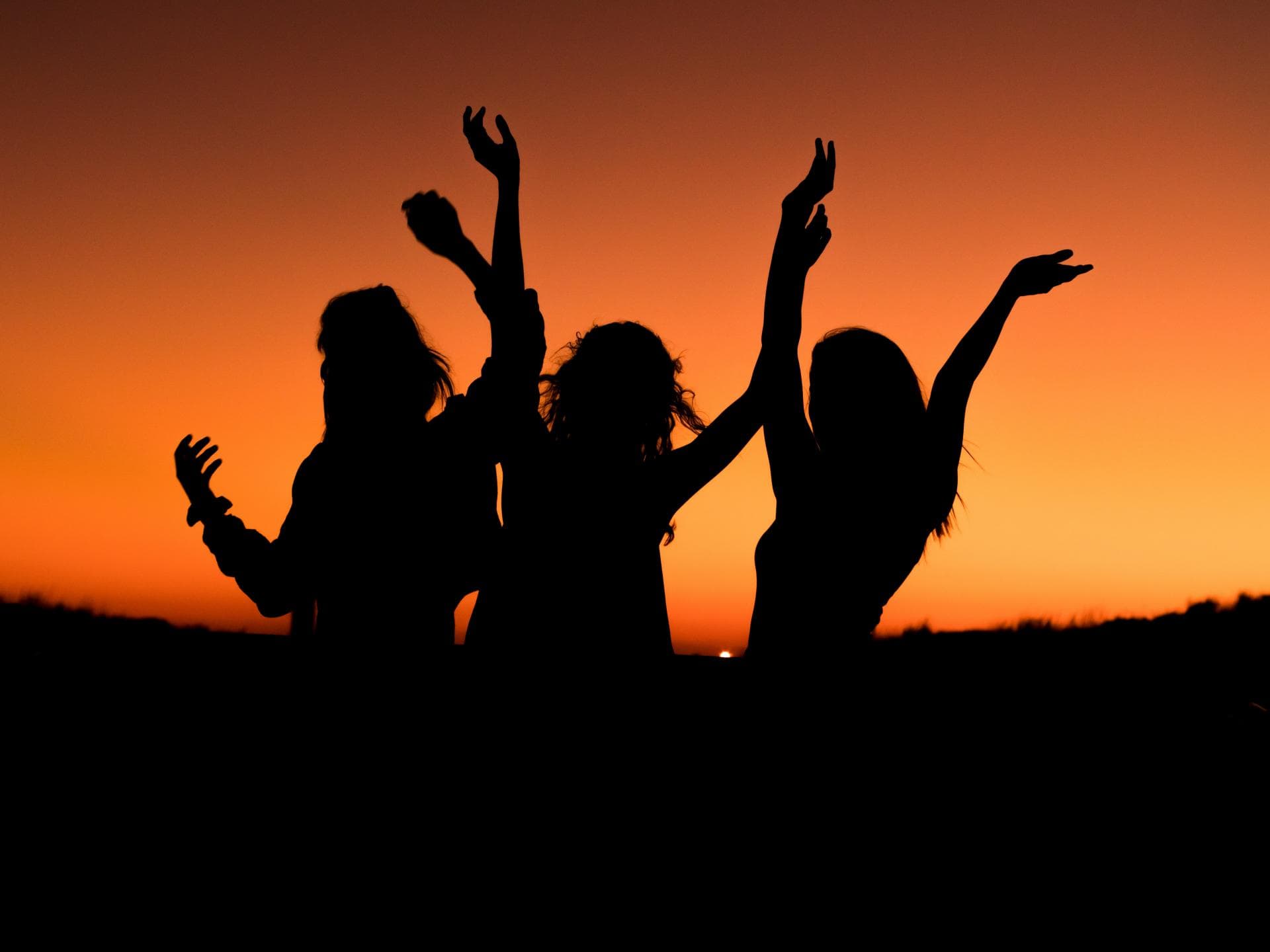 Drei Silhouetten von Frauen vor Sonnenuntergang