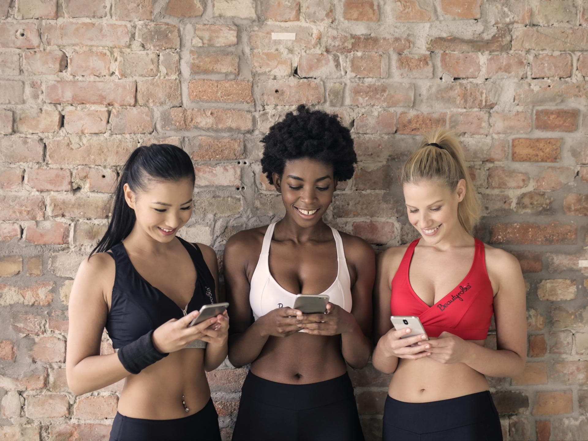 Drei junge Frauen schreiben auf ihren Smartphones